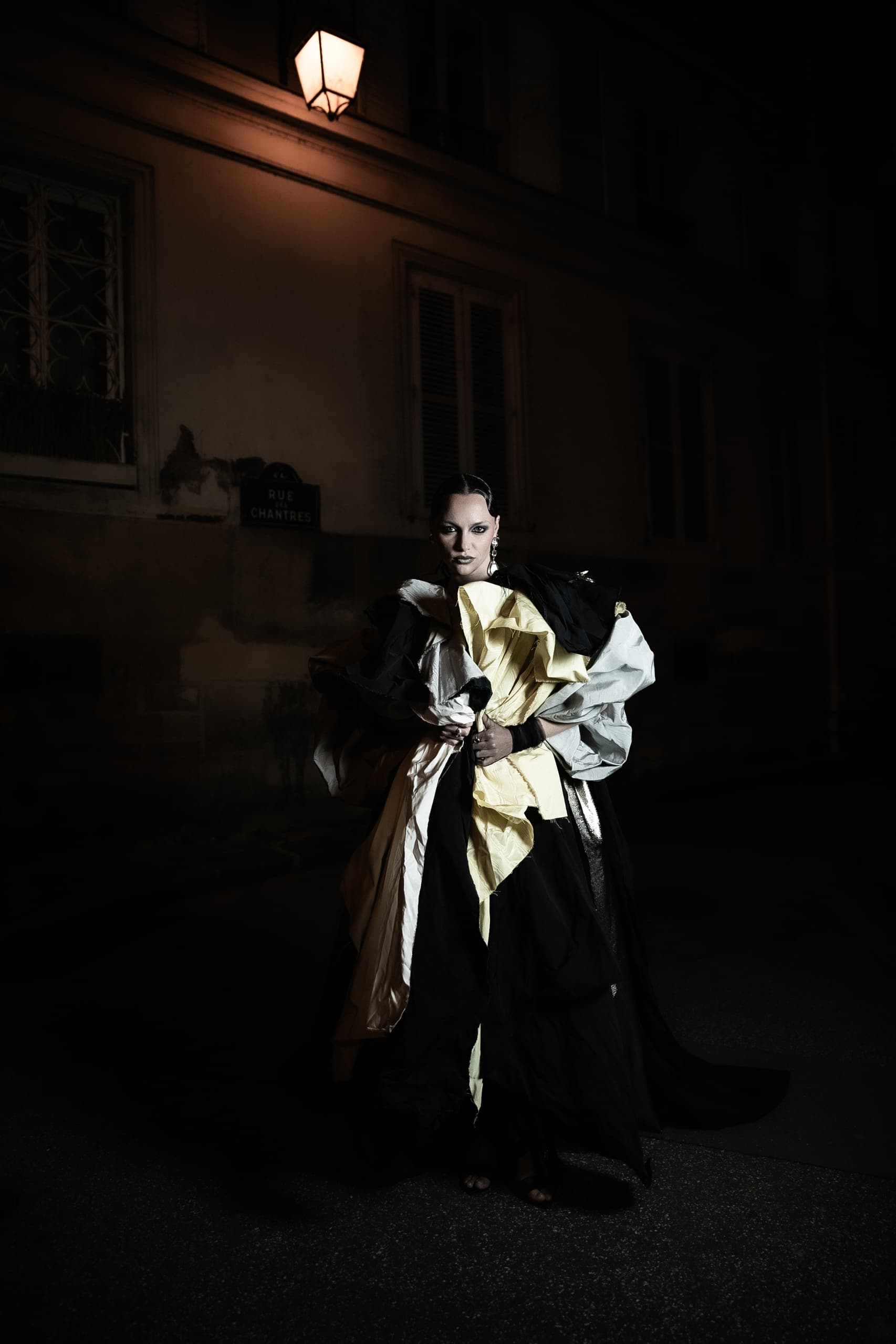 Person in avant-garde fashion under a streetlight at night.