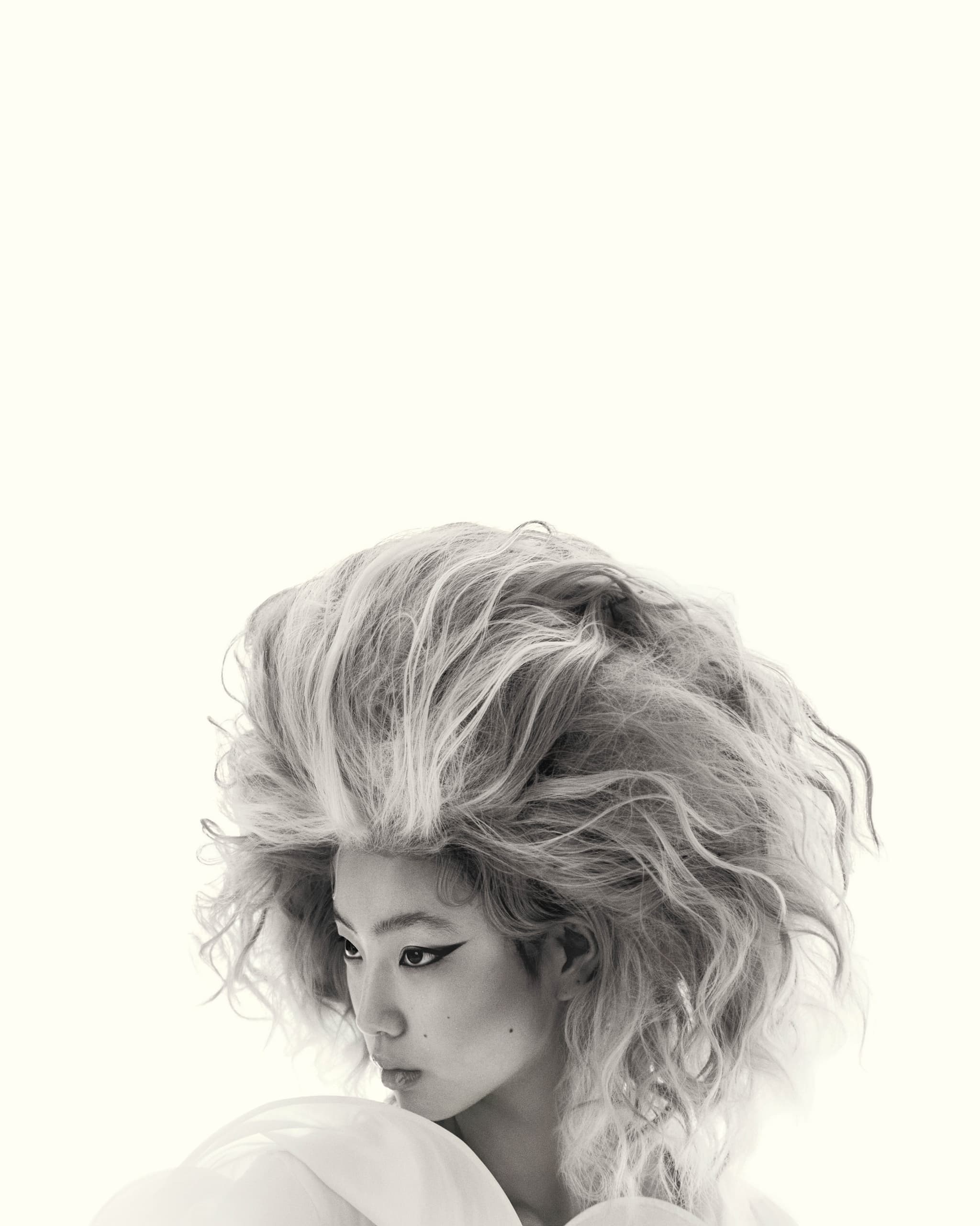Futuristic fashion portrait with bold hair and makeup, grayscale aesthetic.