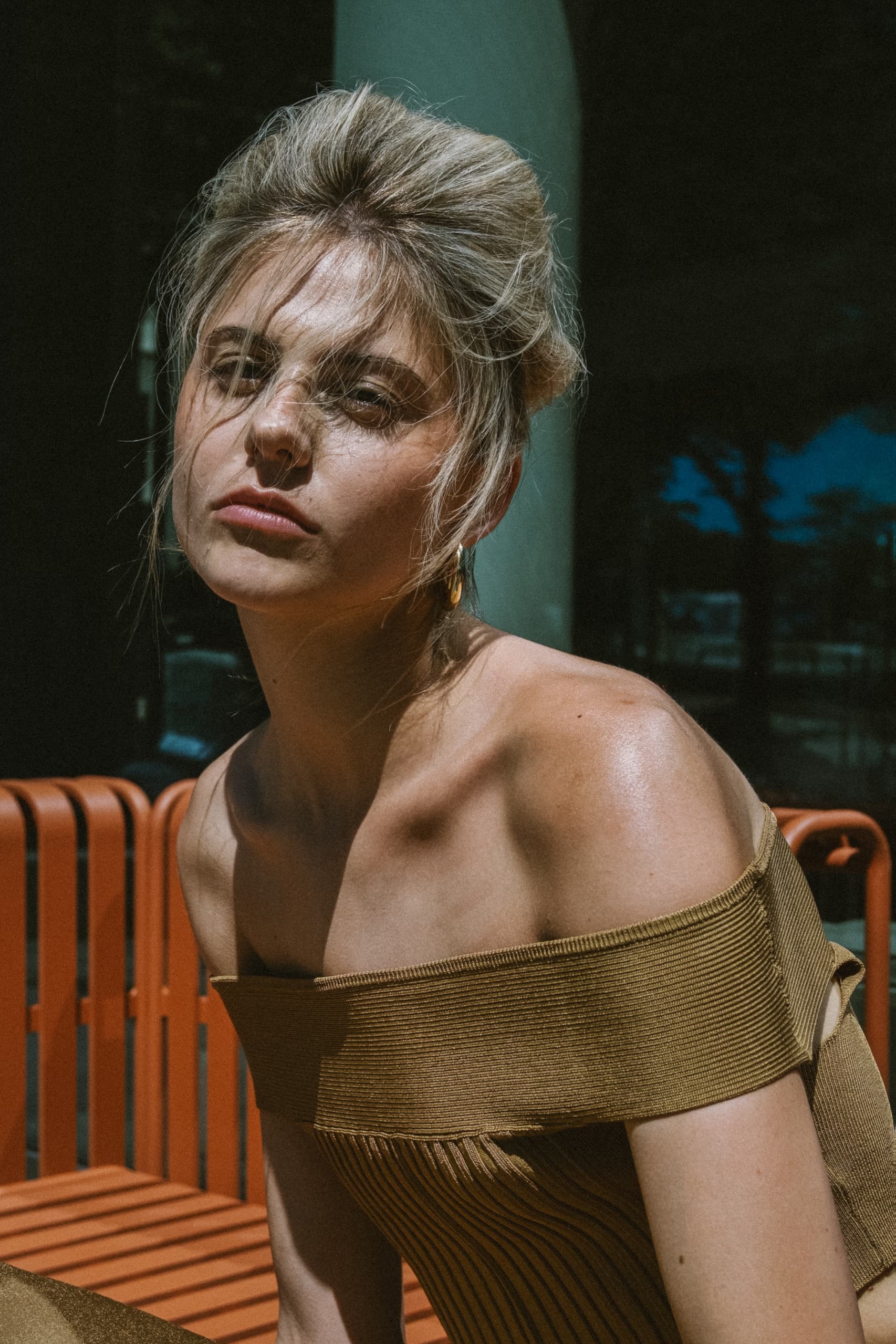 Woman in off-shoulder dress sitting outdoors on sunny day.