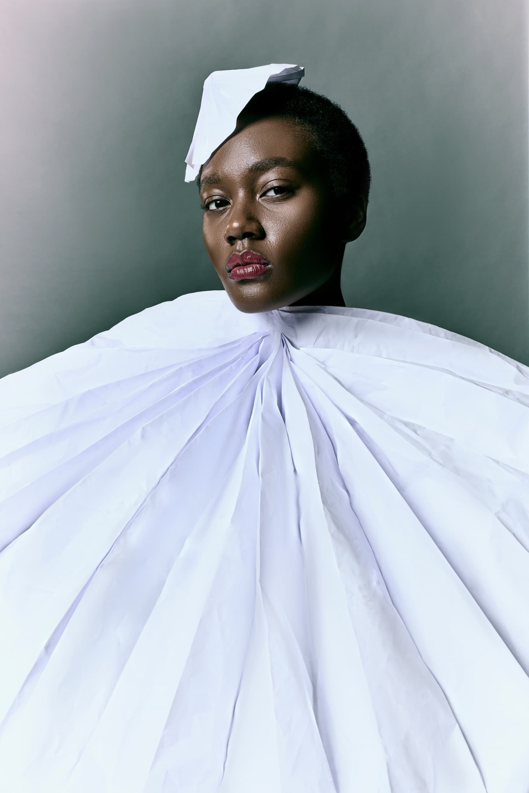 Fashion portrait with striking white paper outfit and elegant headpiece.