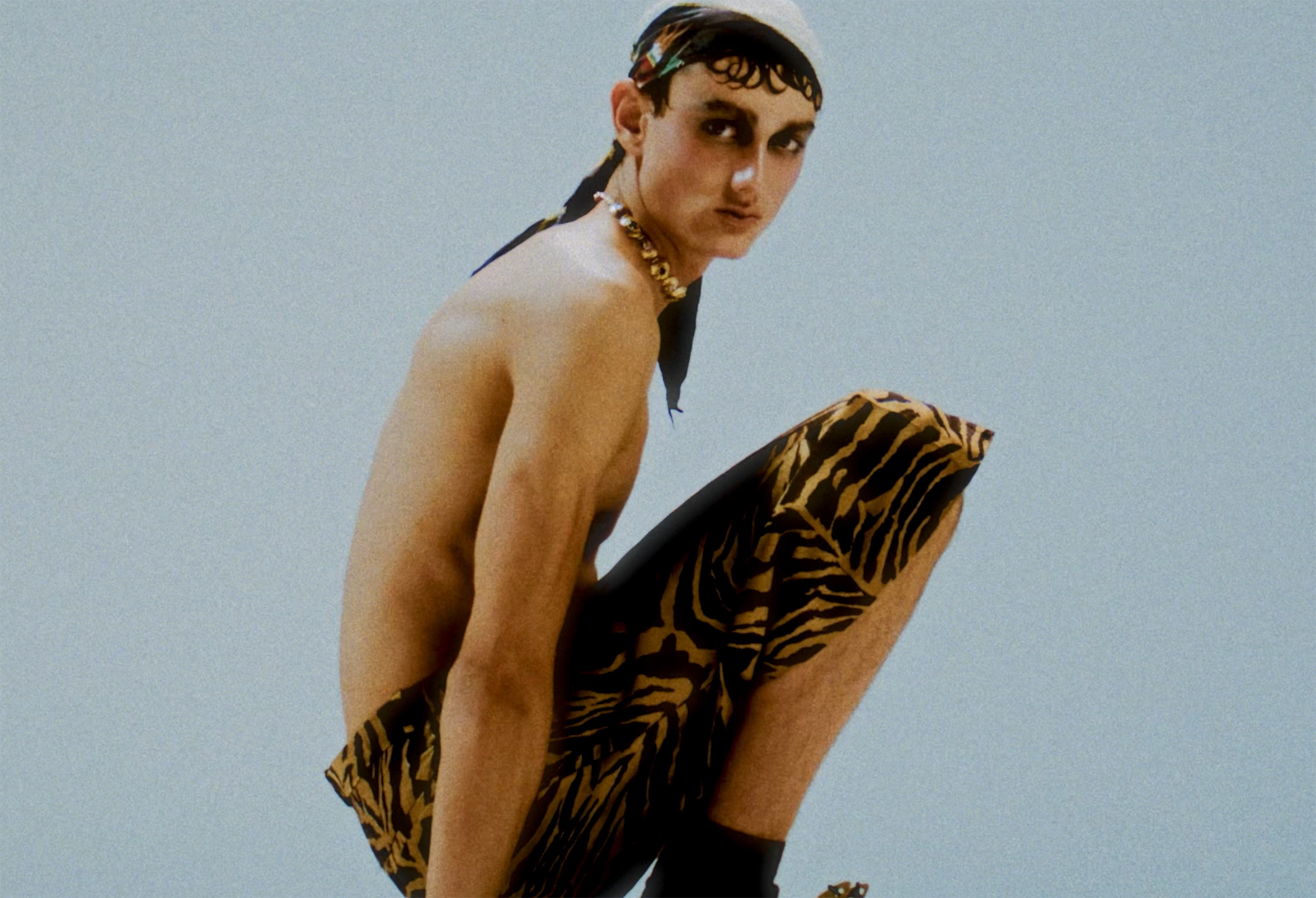Person in leopard print shorts and headscarf, striking a crouched pose. Fashion statement.
