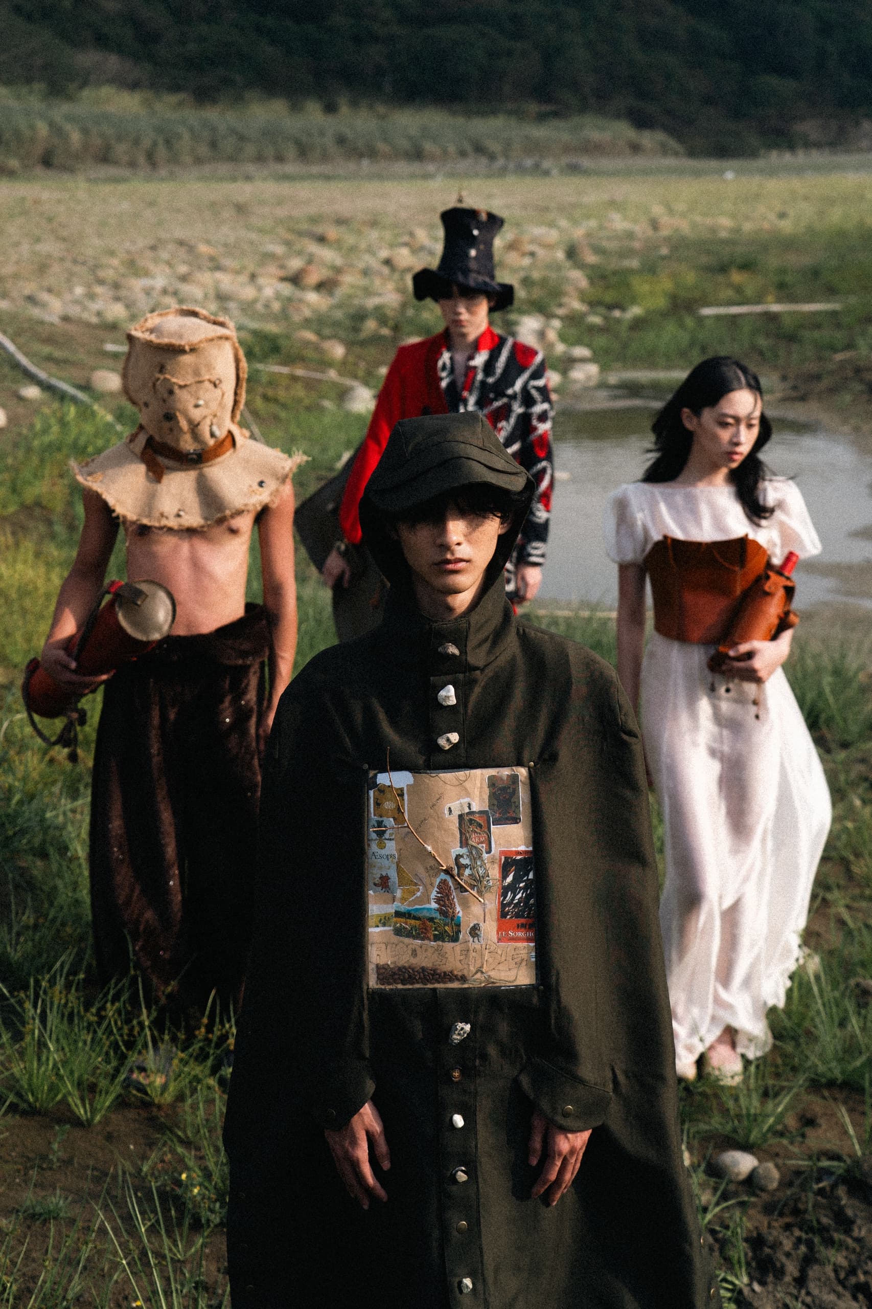 Four people in eclectic, artistic costumes walking in a natural setting.