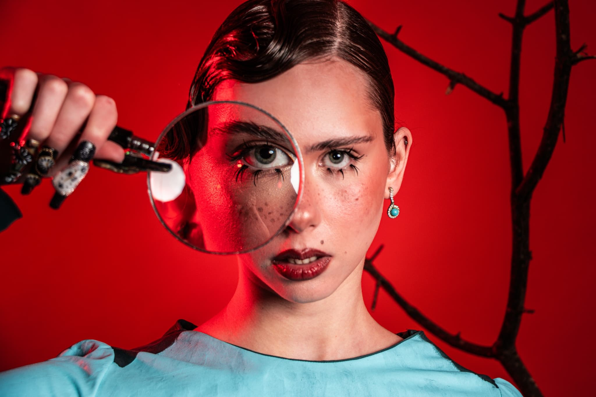 Woman with magnifying glass against red background.