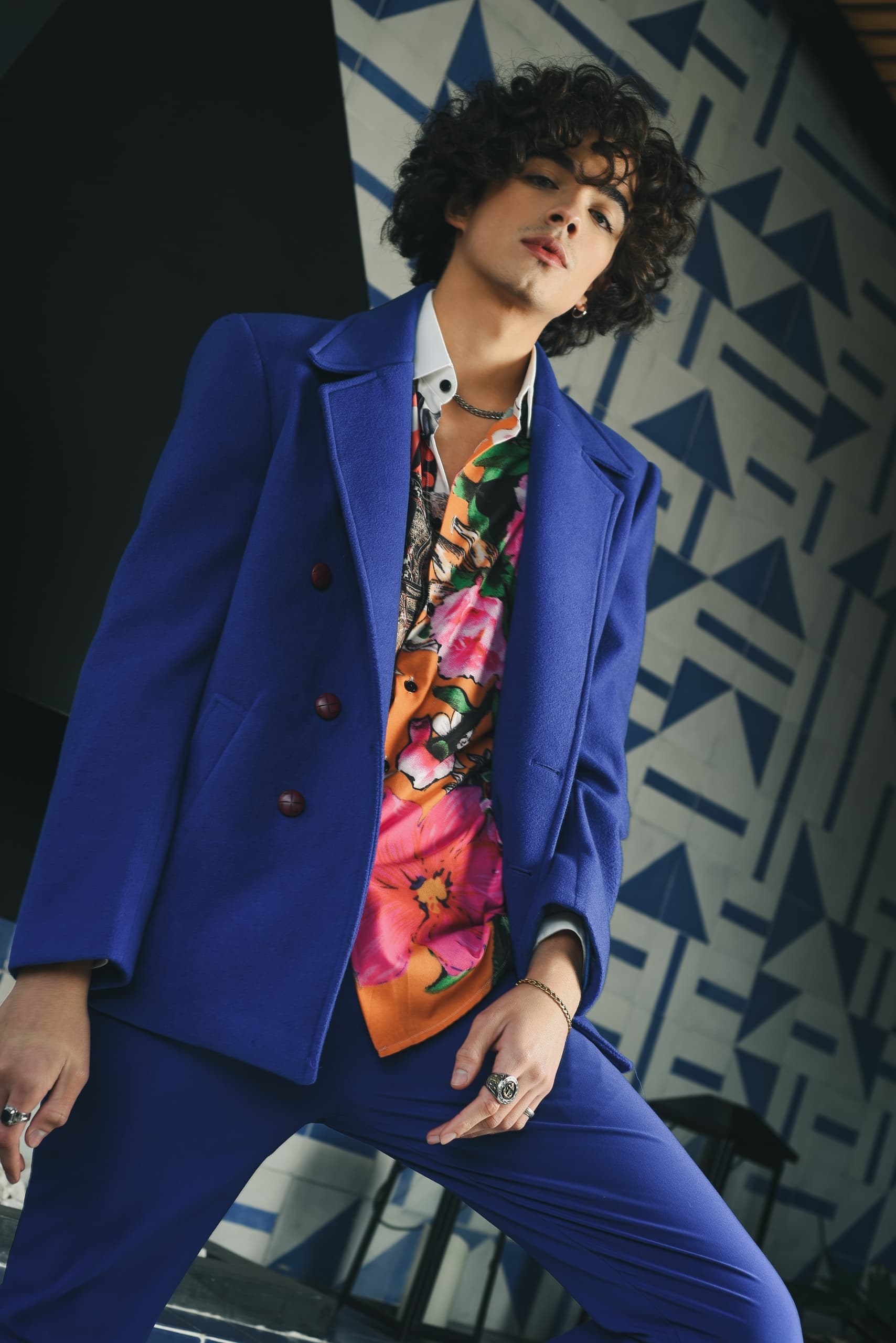 Stylish man in blue suit and floral shirt, geometric background. Fashion statement.