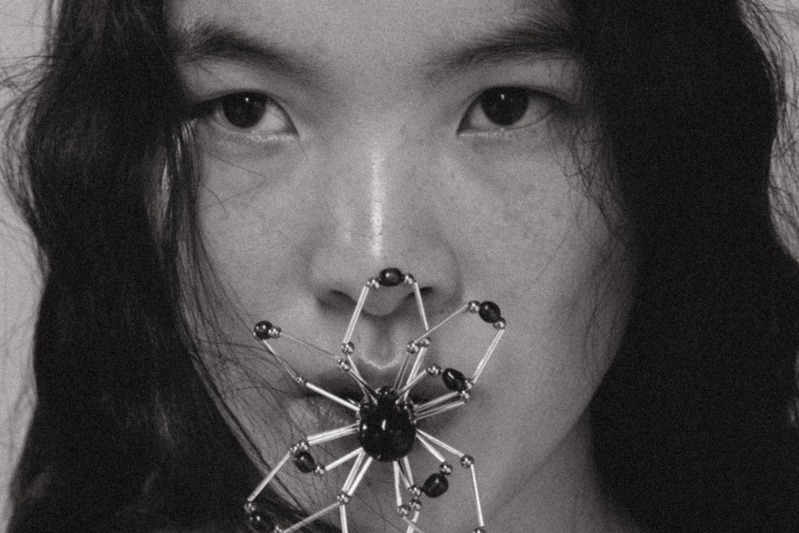 Person with a spider-shaped accessory on face in black and white.