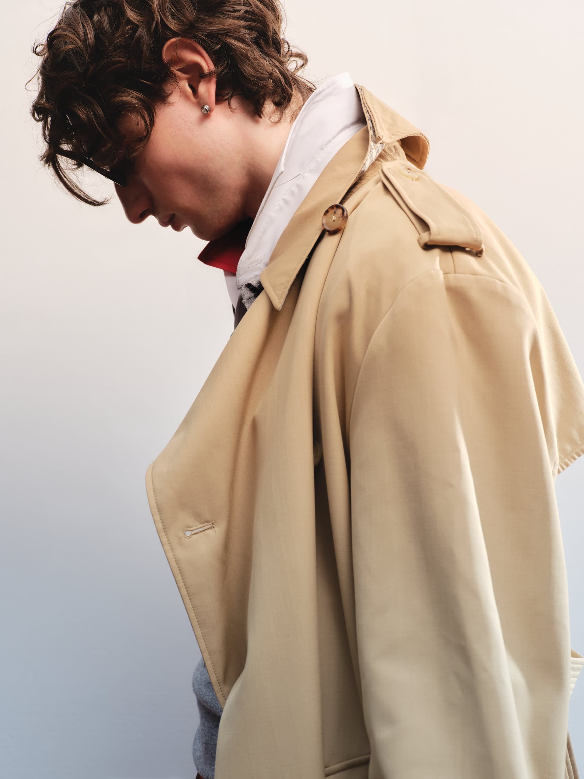 Profile of person in beige trench coat, modern style fashion.