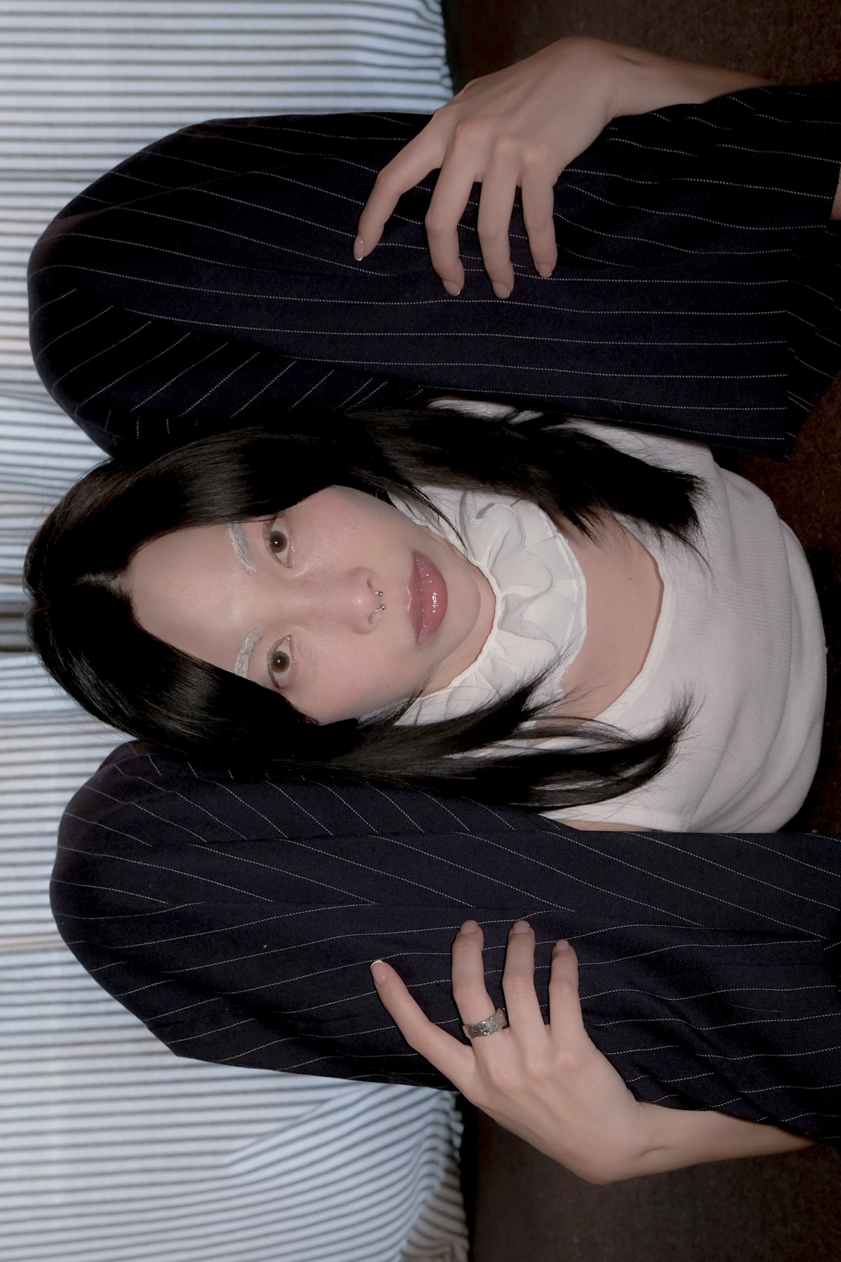 Person in a unique pose with legs over shoulders, wearing a pinstripe suit and white top.