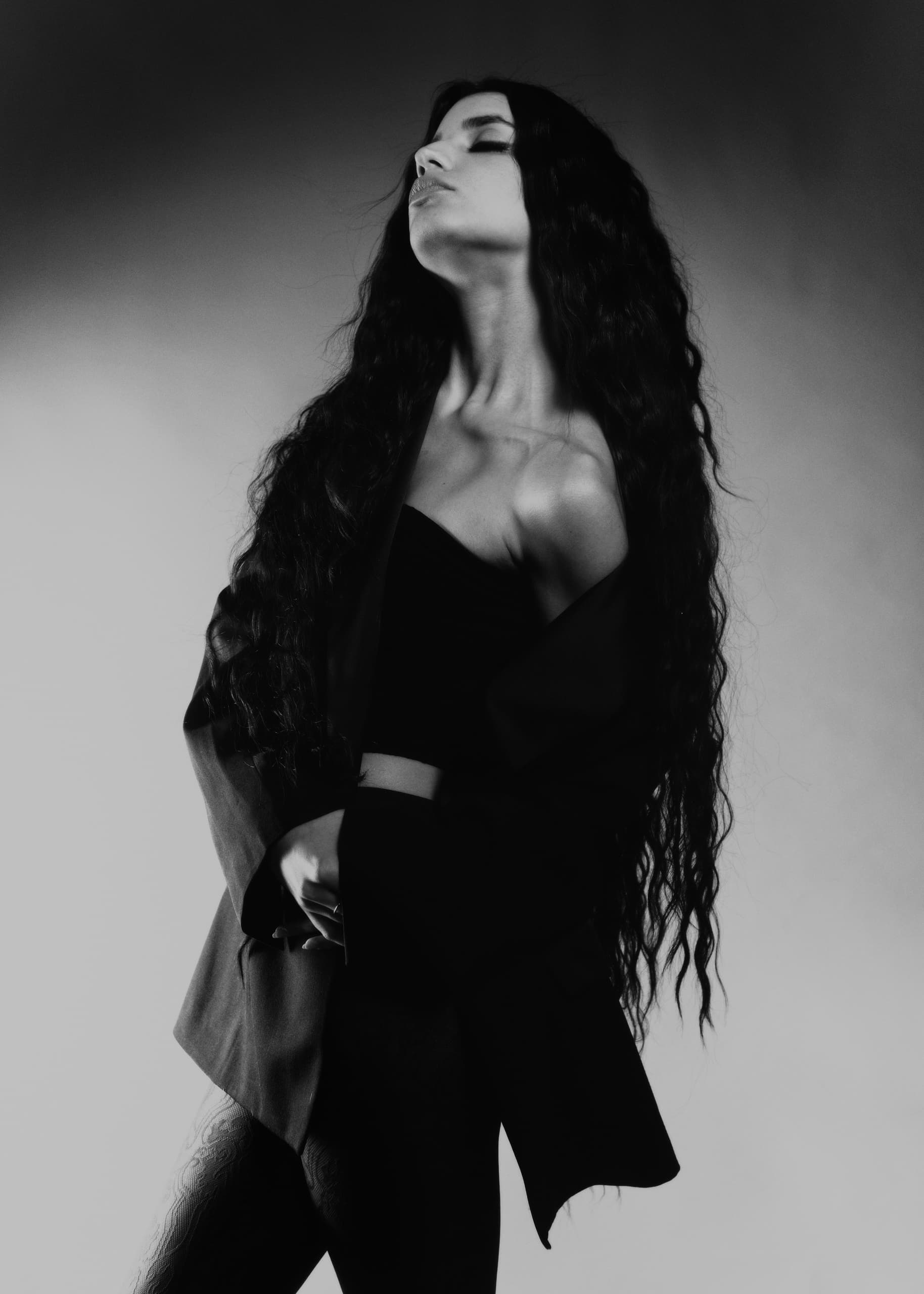 Woman in black and white, posing with long hair and stylish attire.