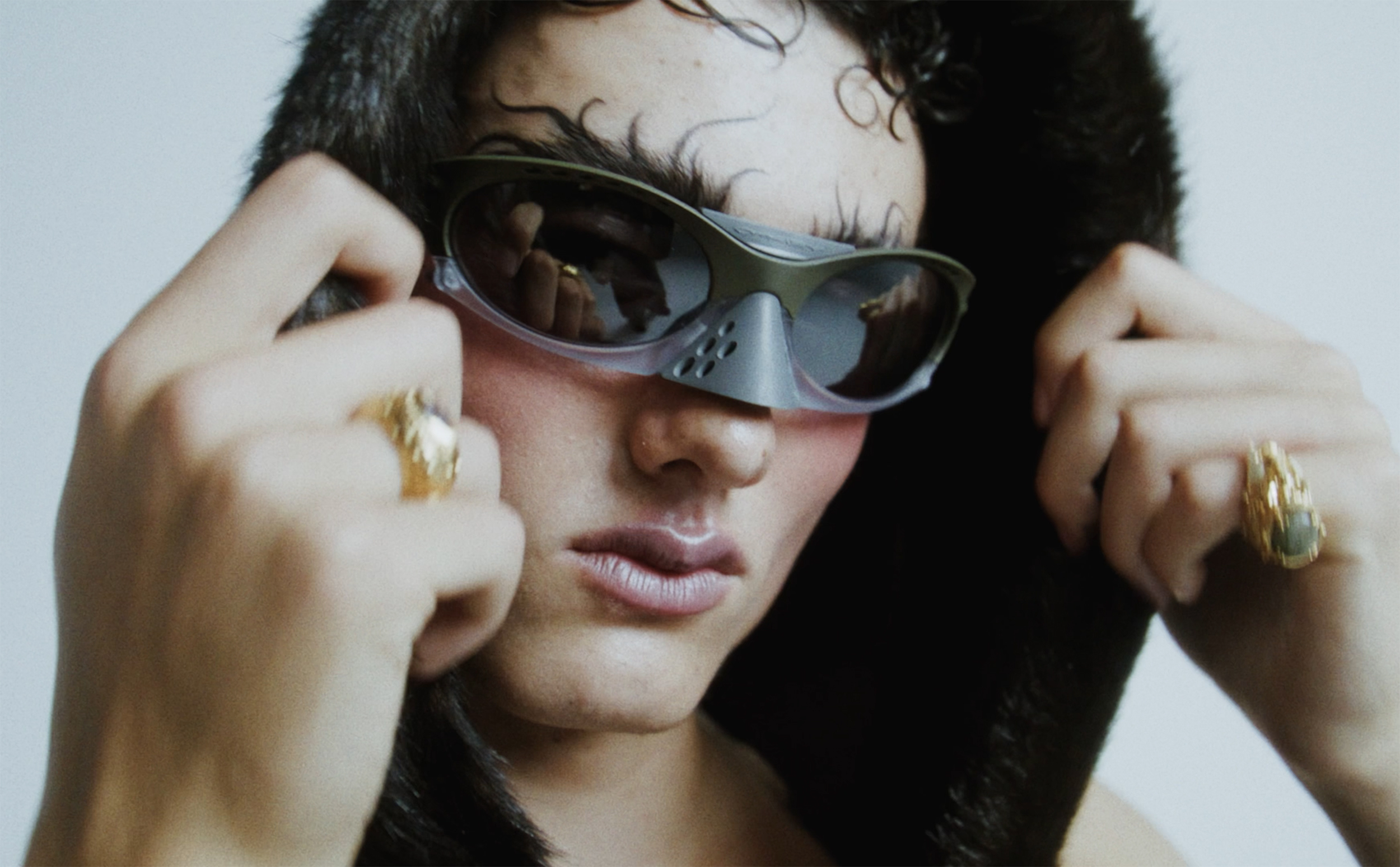 Fashionable person wearing unique sunglasses and fur hood, close-up.