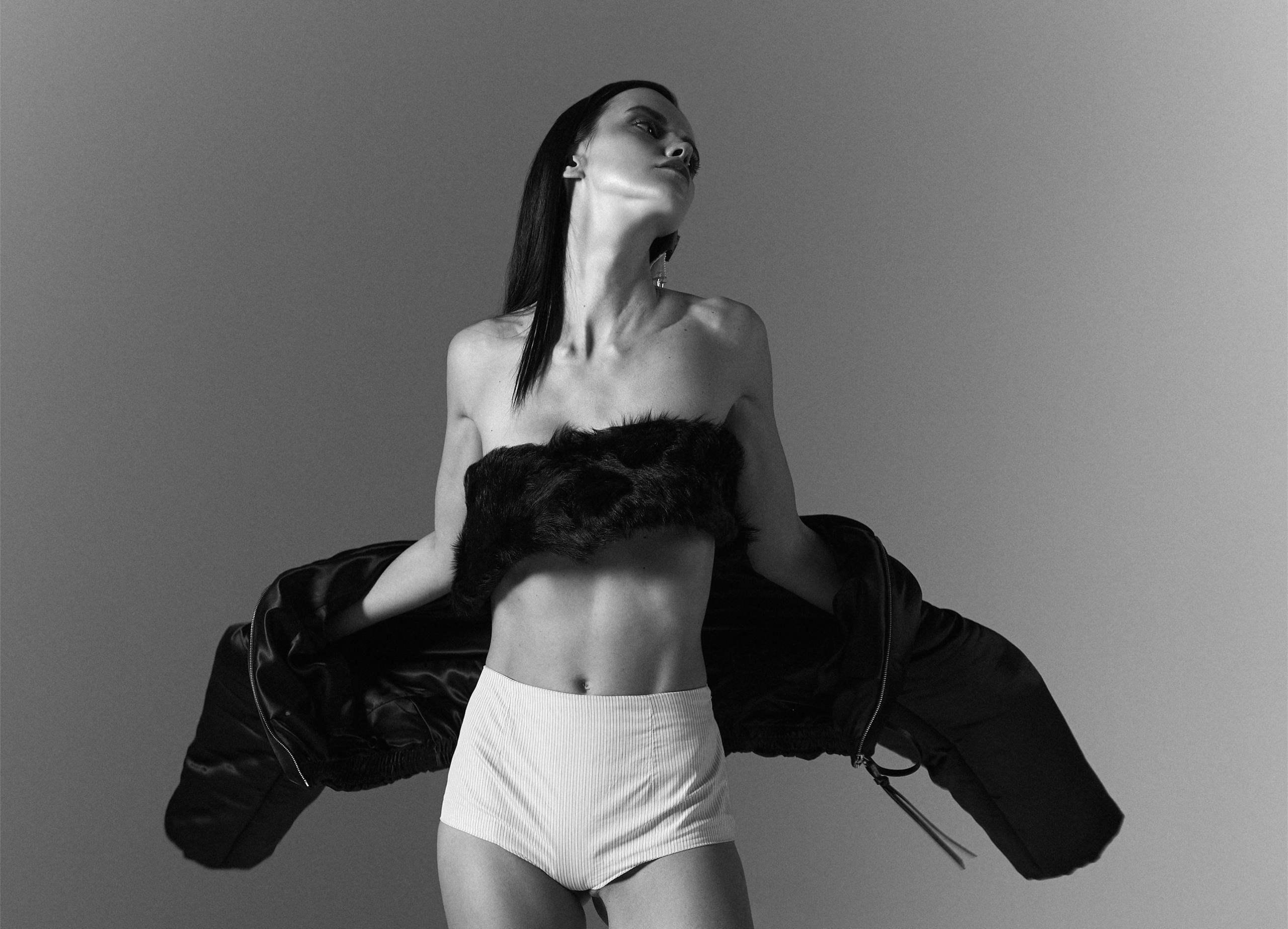 Fashion model in high-waisted shorts and fur top, striking a dramatic pose.