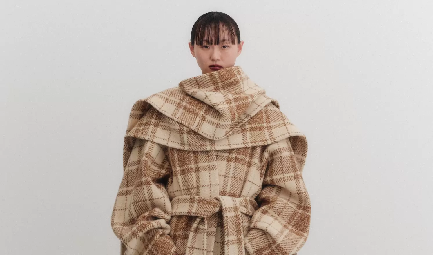 Plaid wool coat with oversized collar on model in neutral background.