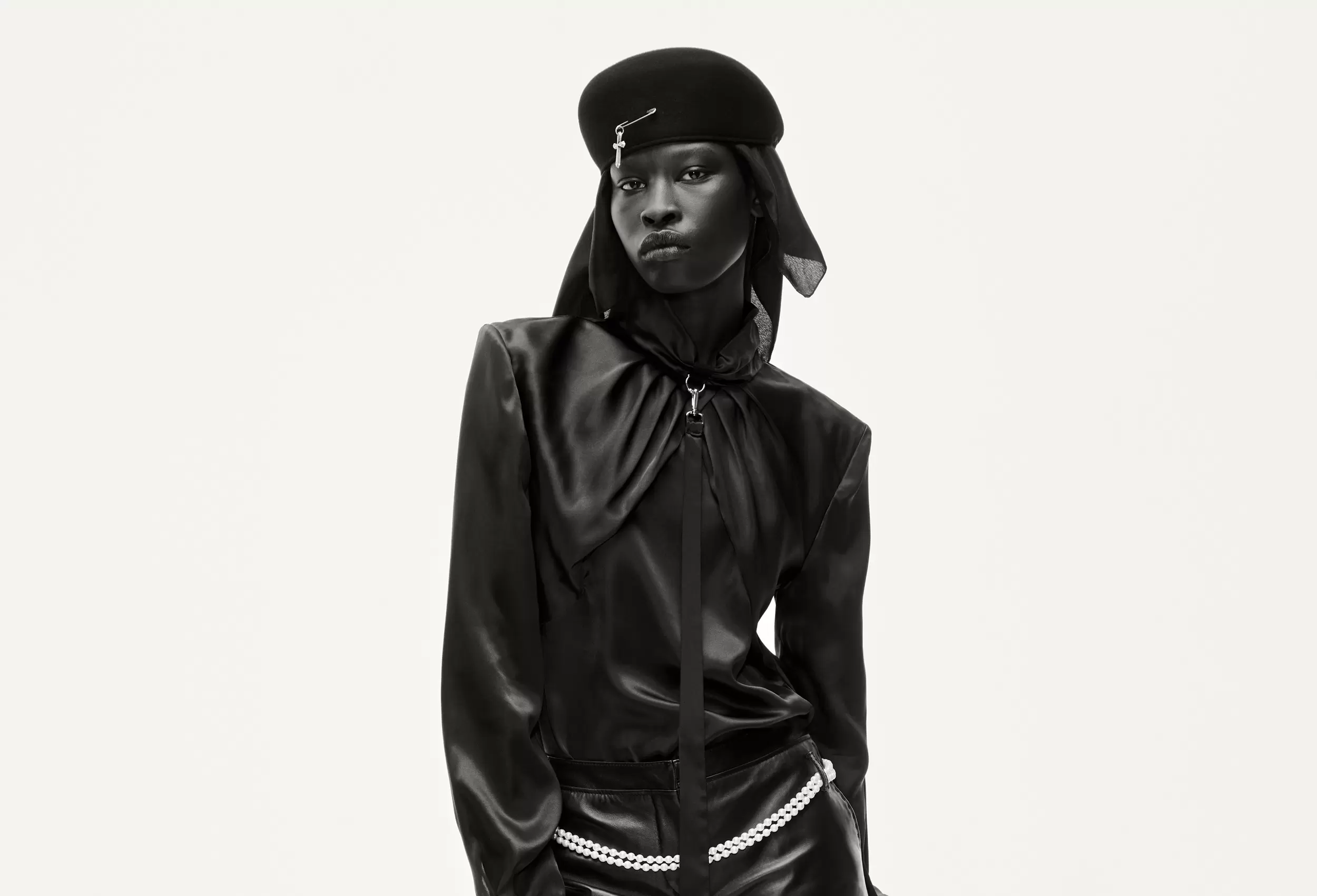 Fashion model in sleek black outfit with cap, exuding modern elegance.