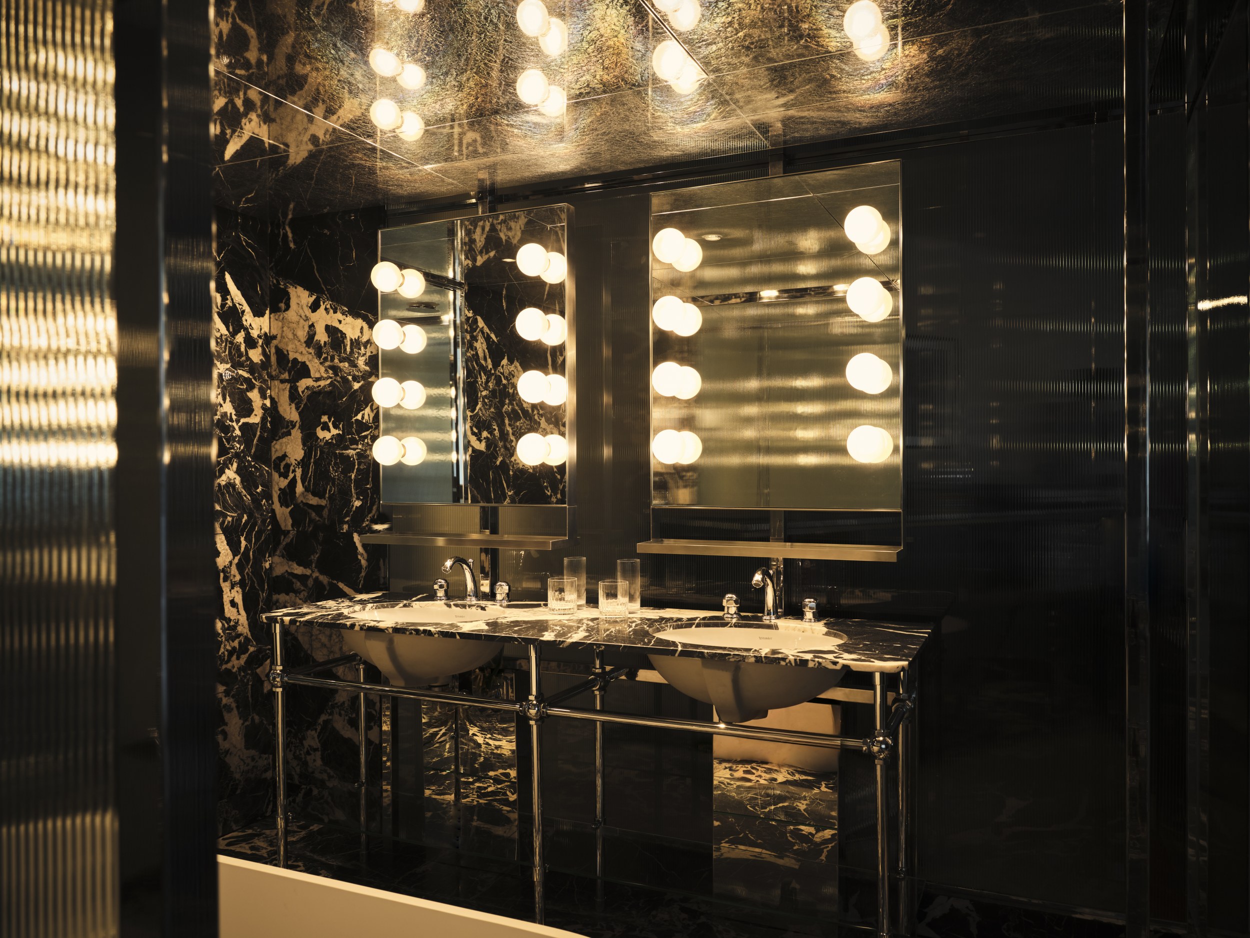 Luxurious marble bathroom with well-lit mirrors and elegant double sink.