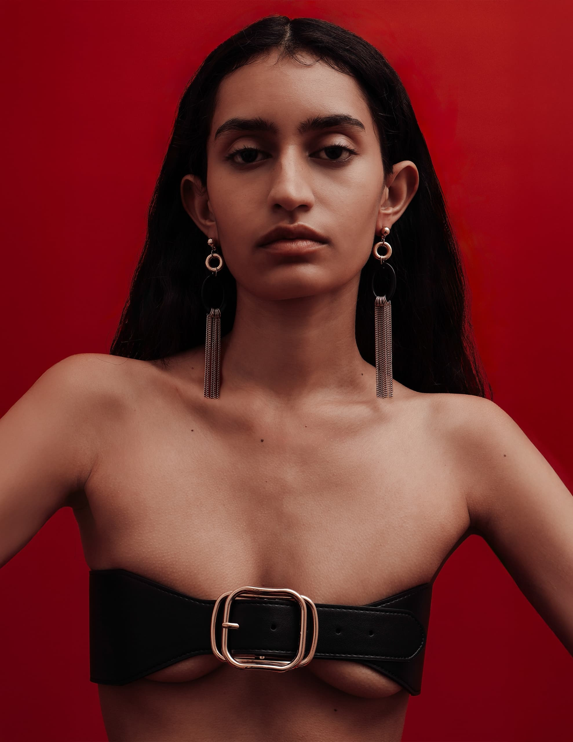 Fashion model in a bold black band top against a vibrant red background.