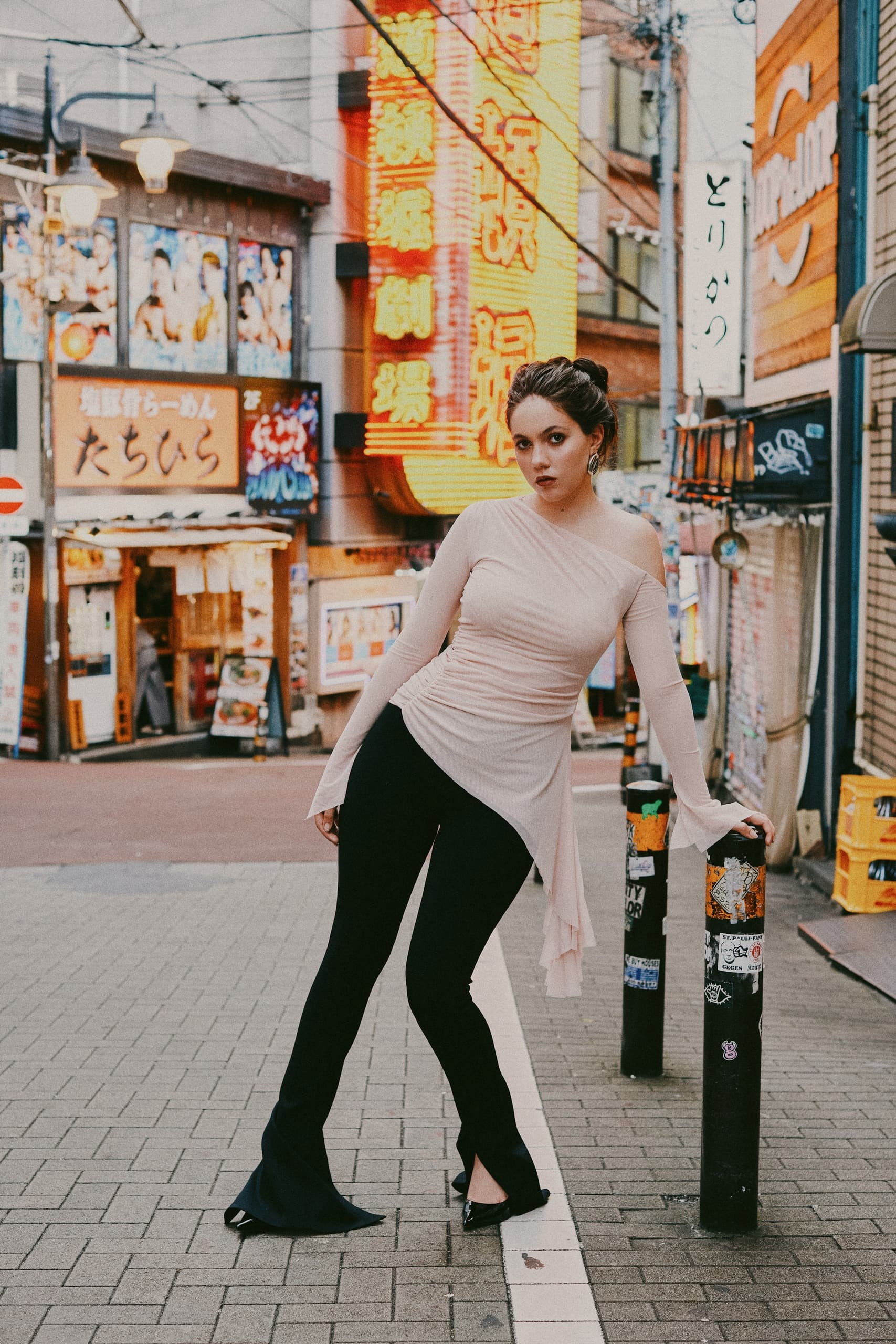 Fashionable person posing in a vibrant city street with neon signs.
