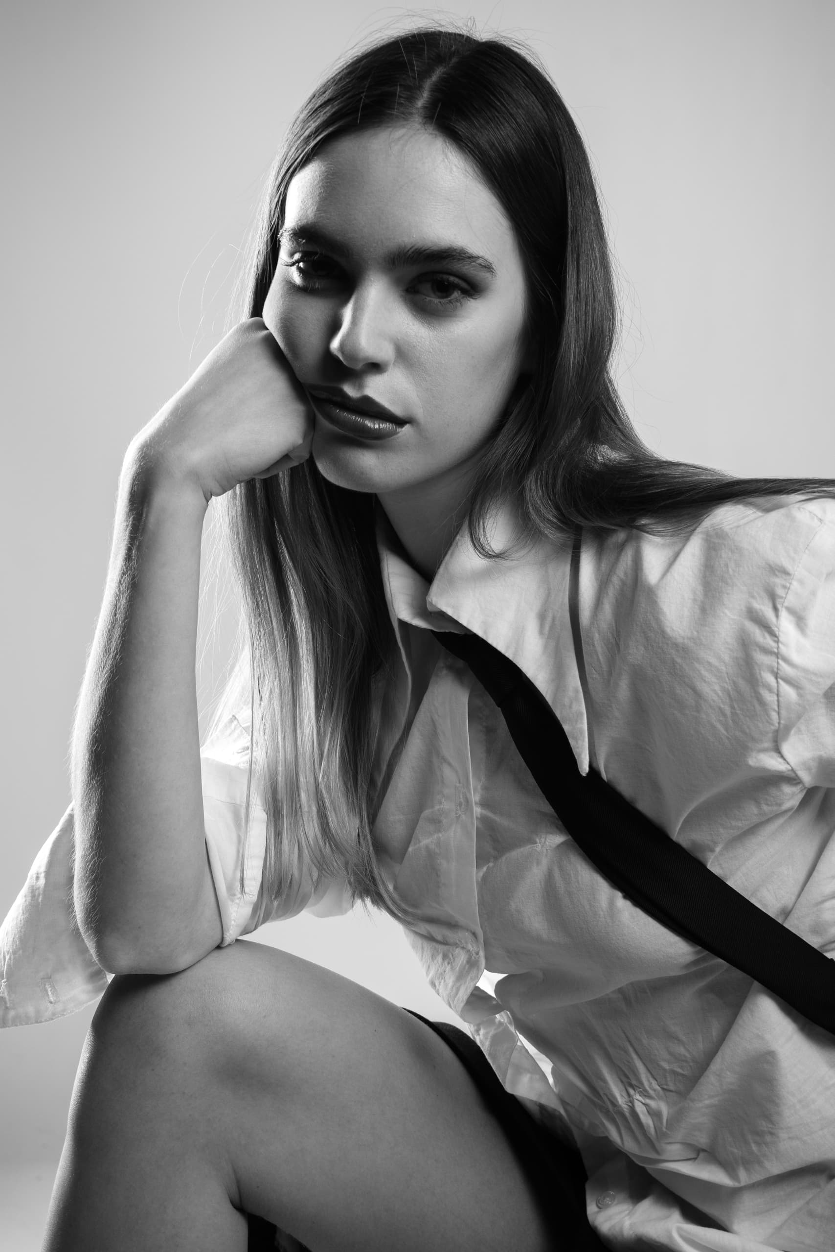 Black and white portrait of a thoughtful woman in a white shirt.