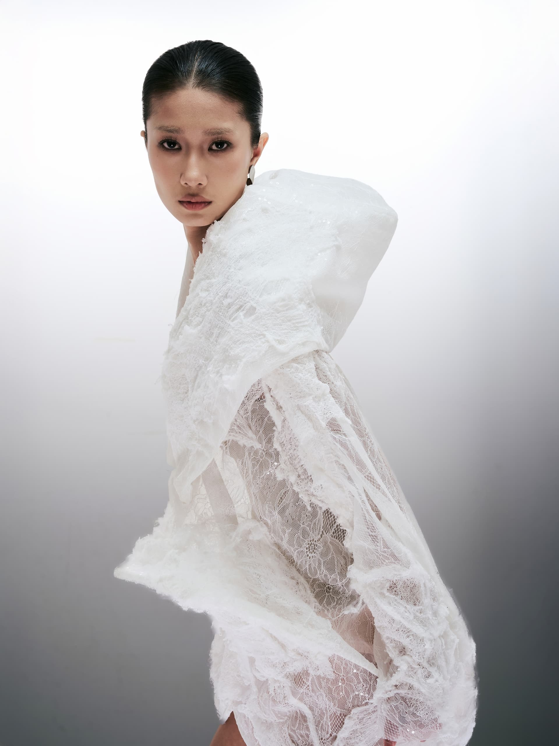 Model in elegant lace outfit against a minimalist white background.