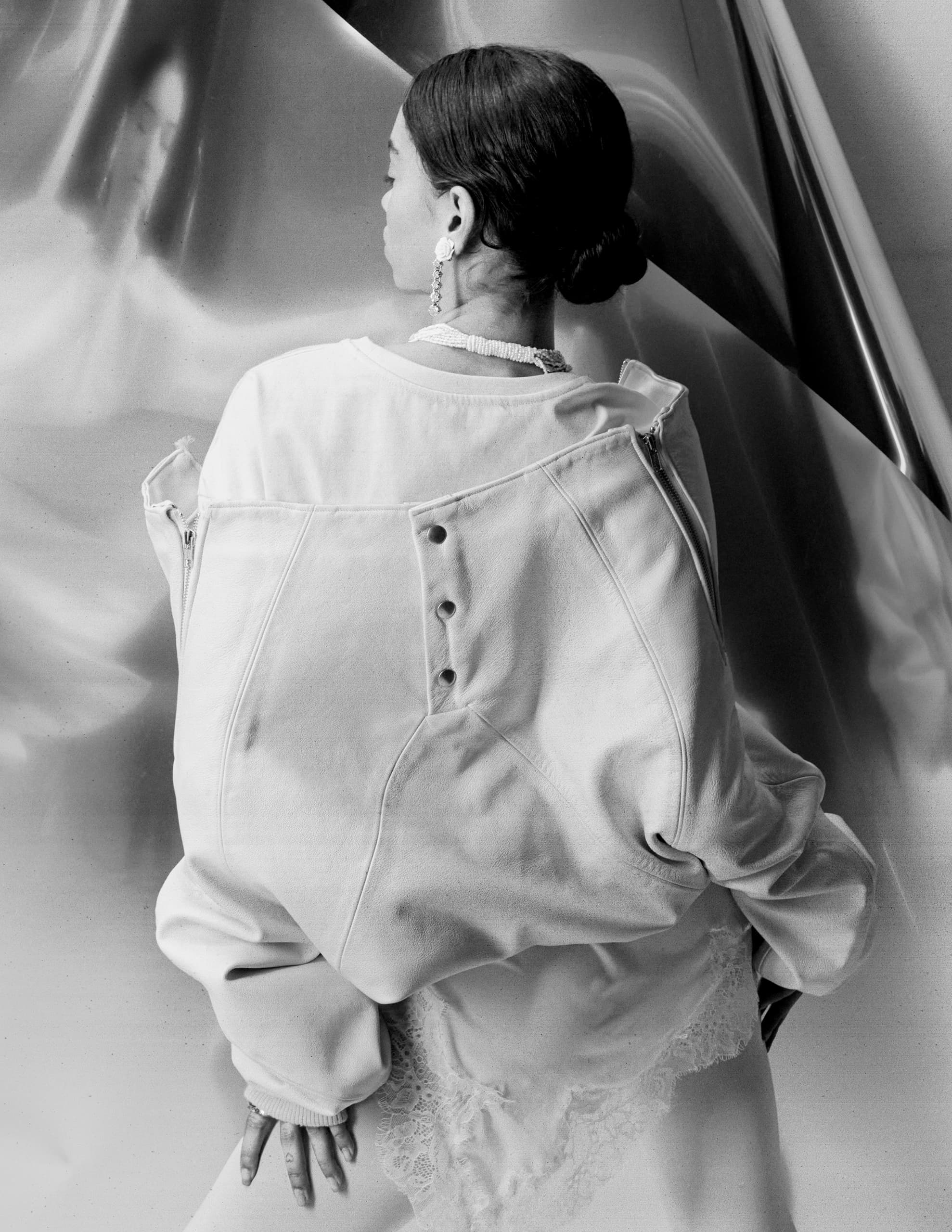 Black and white photo of woman in oversized jacket, looking away.