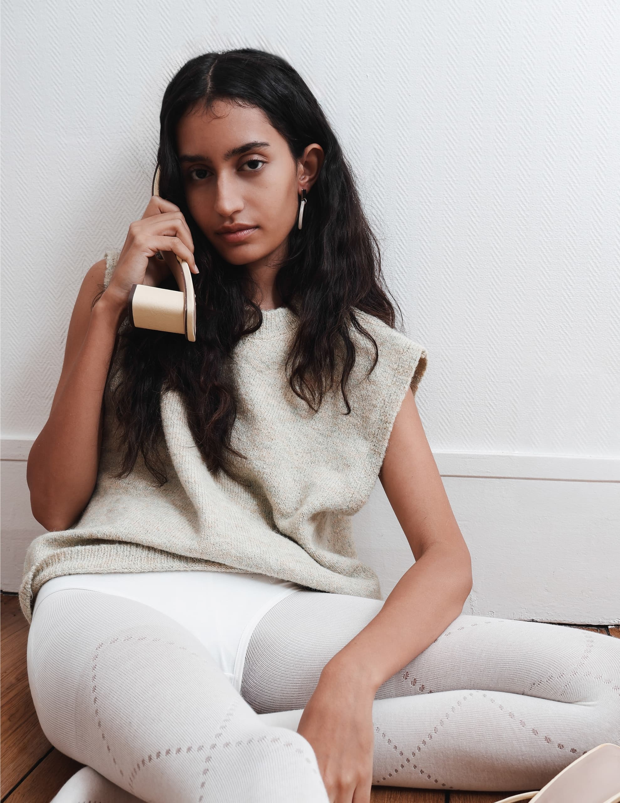 Woman with long hair using a vintage beige telephone while sitting on the floor.