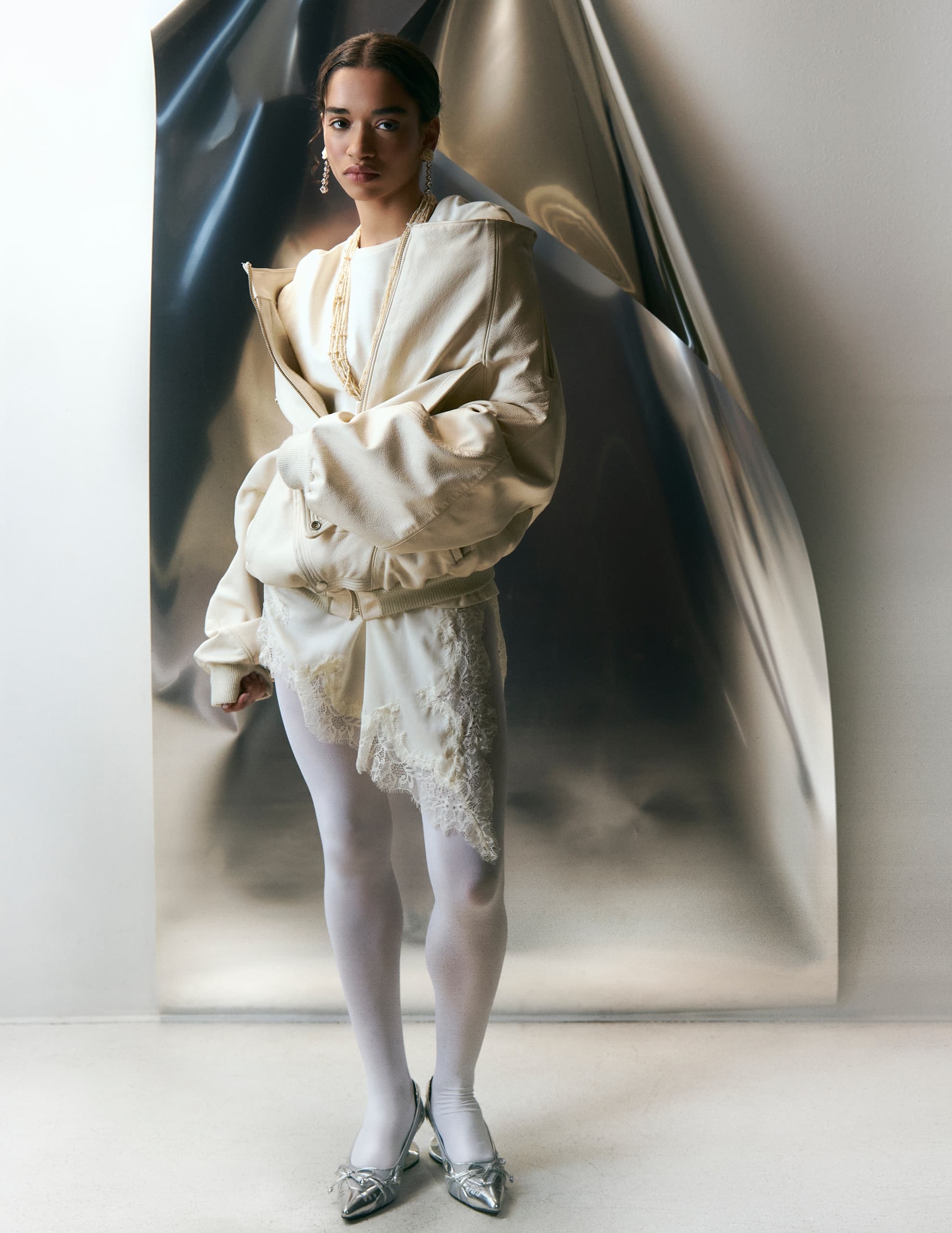 Fashion model in elegant white outfit with metallic background.