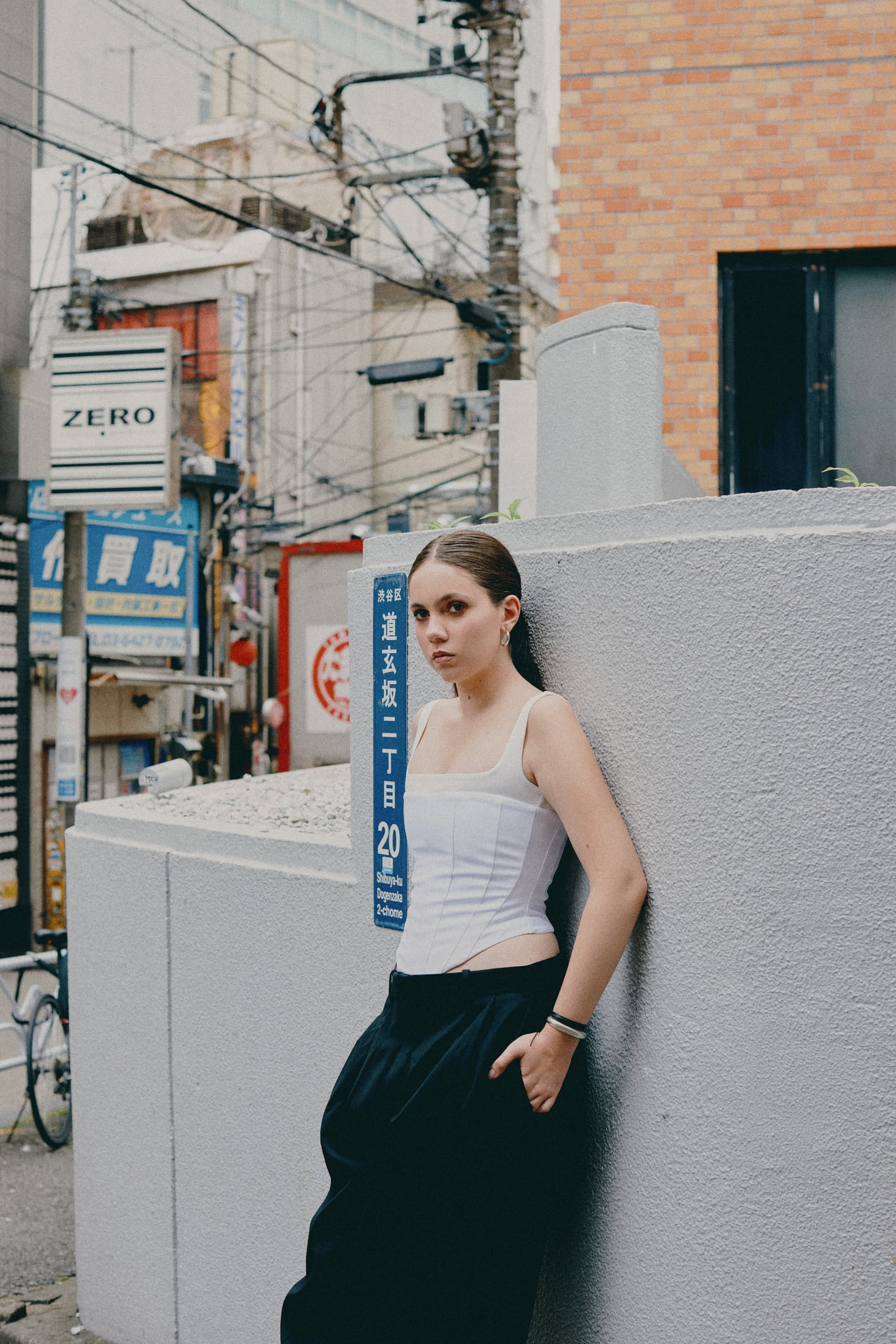 Person in urban setting, Japan street, leaning on wall, day time scene.