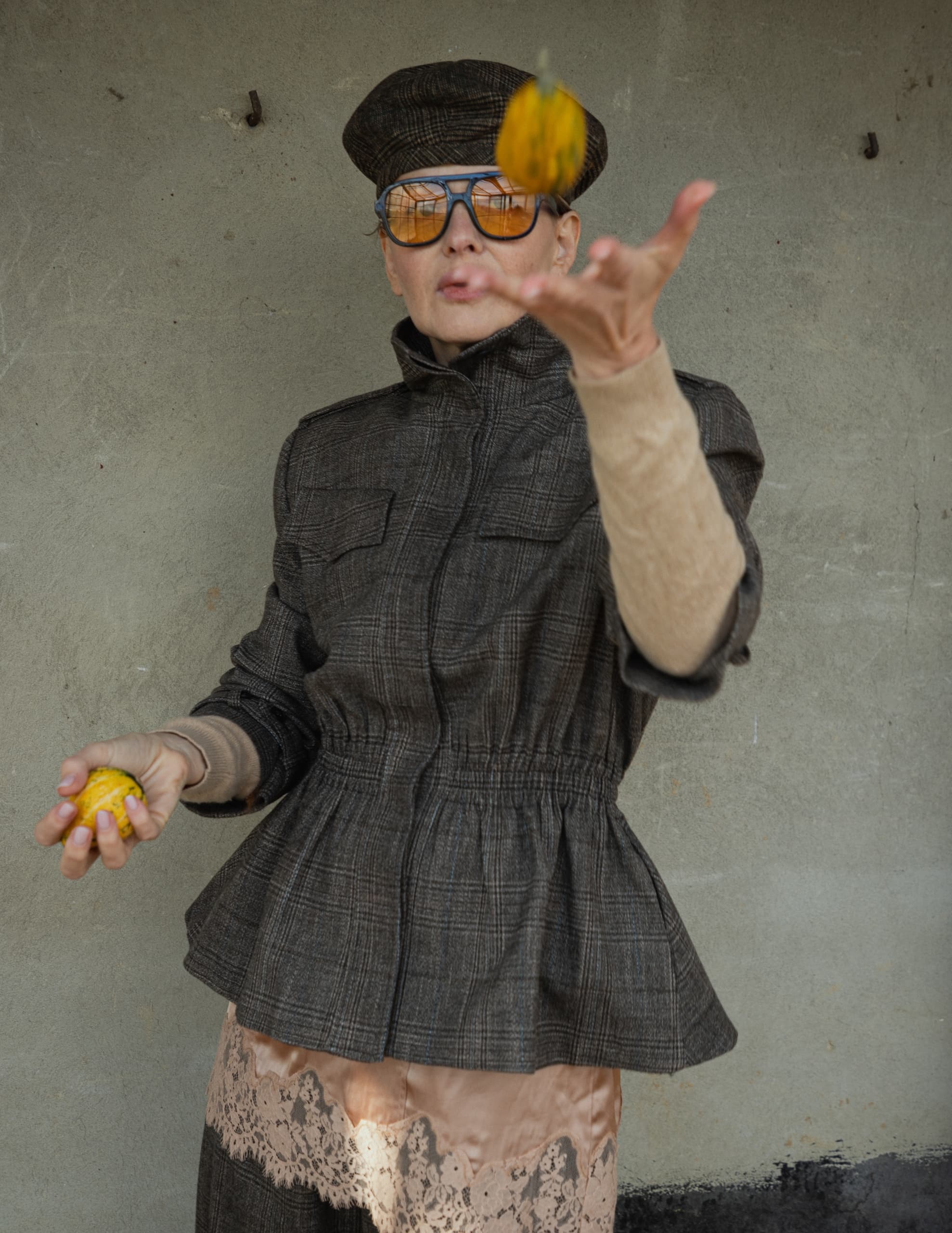 Fashionable person in vintage attire playfully tosses a small gourd.
