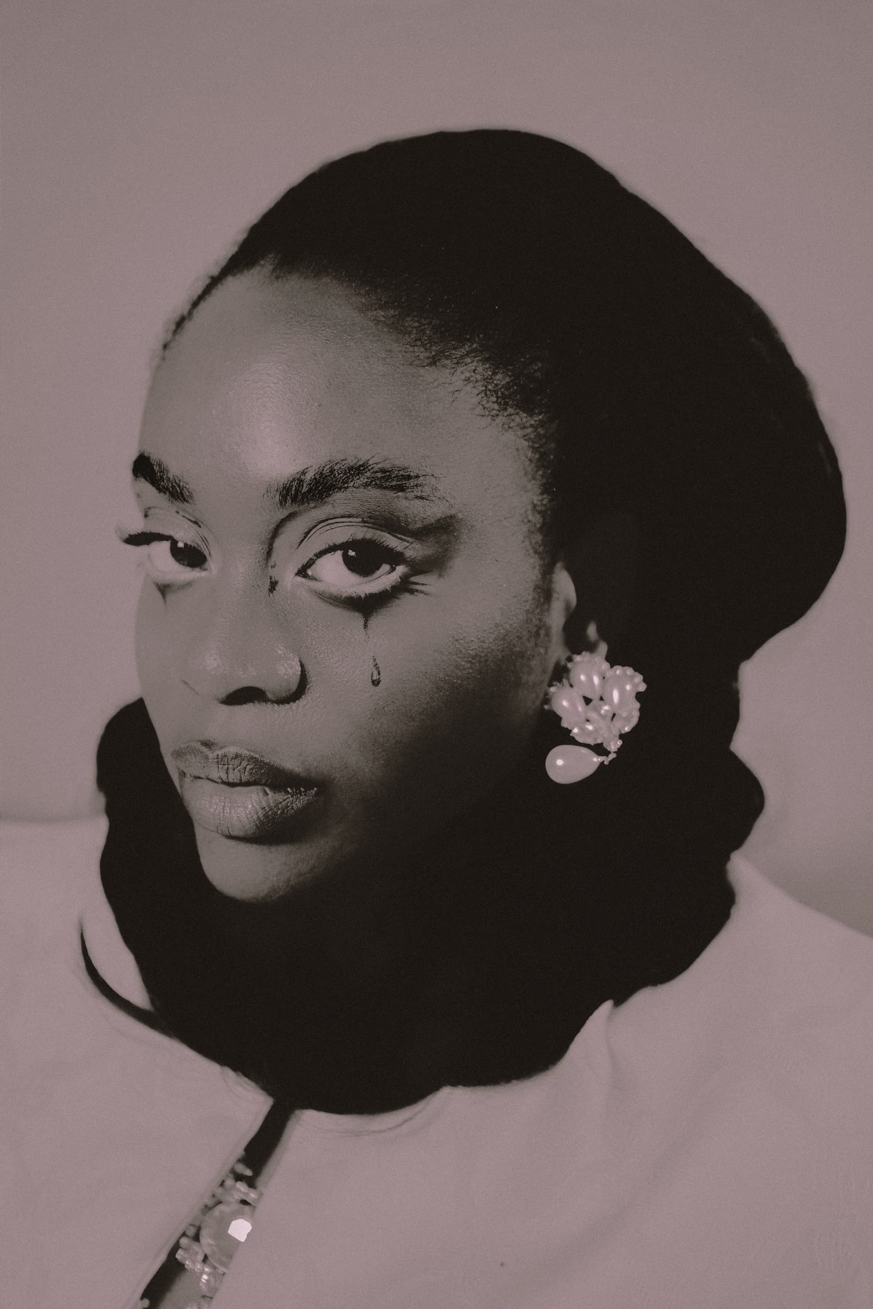 Portrait of a woman with a tear, wearing ornate earrings, black and white style.