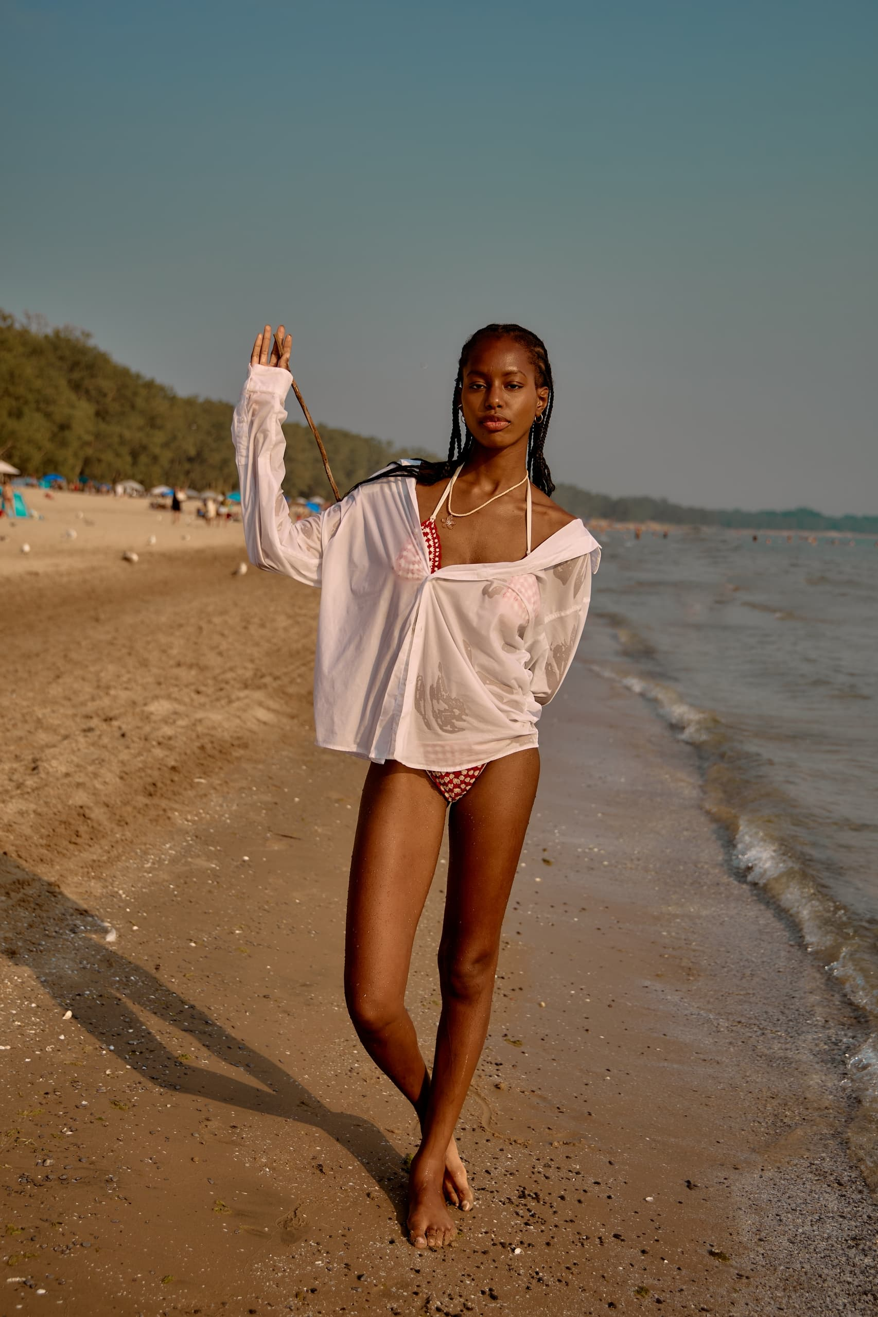 Person in a bikini and sheer cover-up walking on a sunny beach.