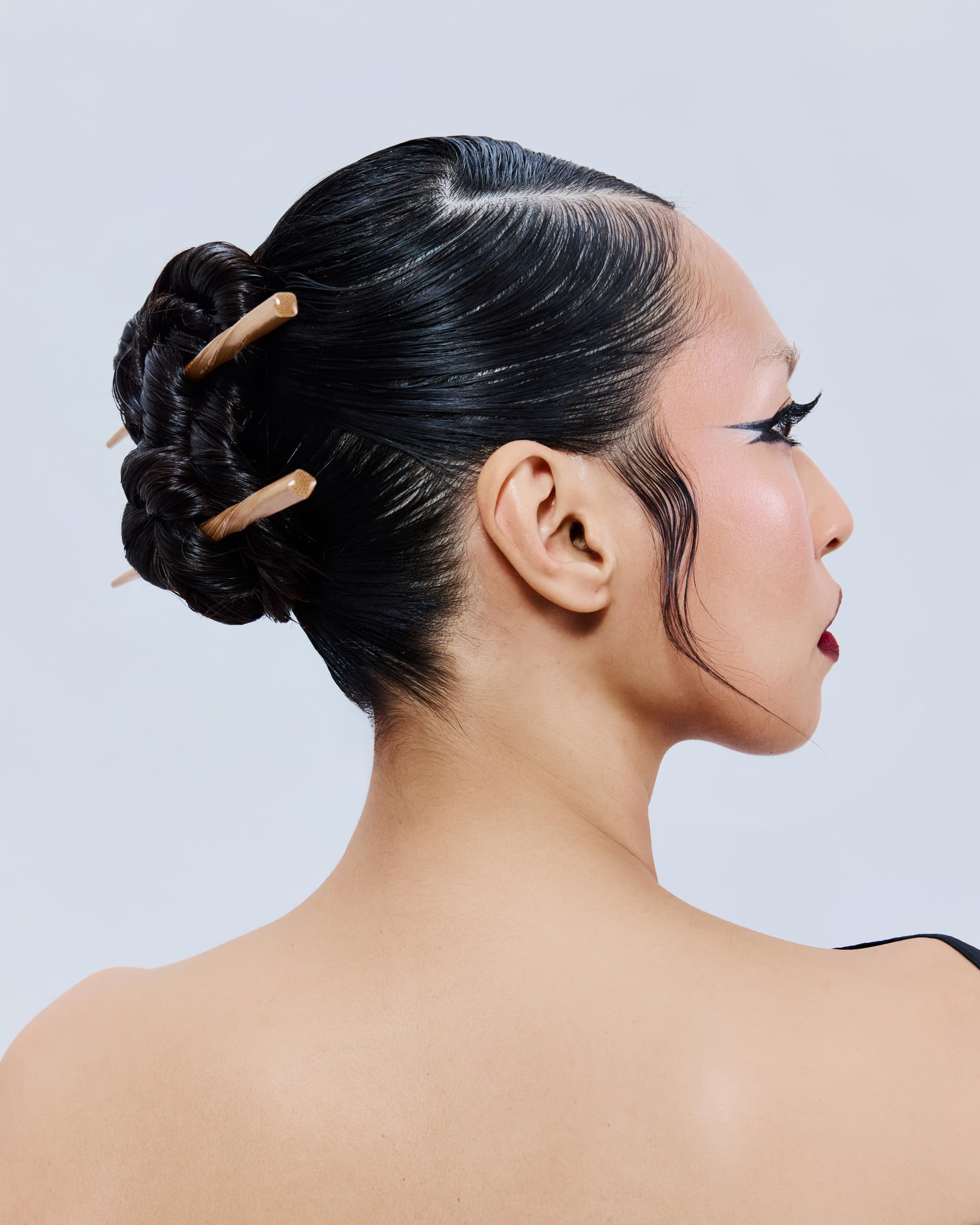 Elegant hairstyle with chopsticks in a sleek bun, side view.