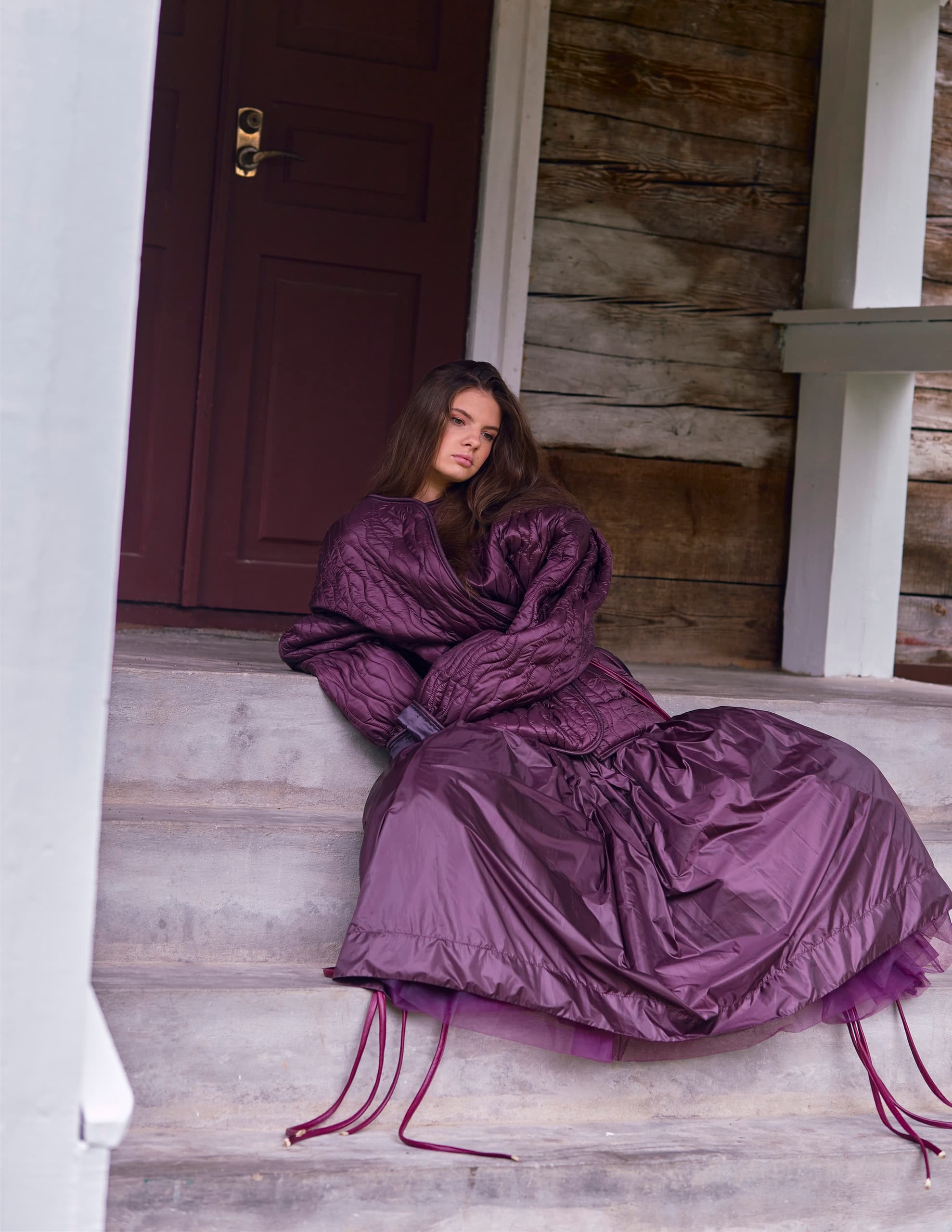 Woman in purple quilted outfit sitting on wooden steps.