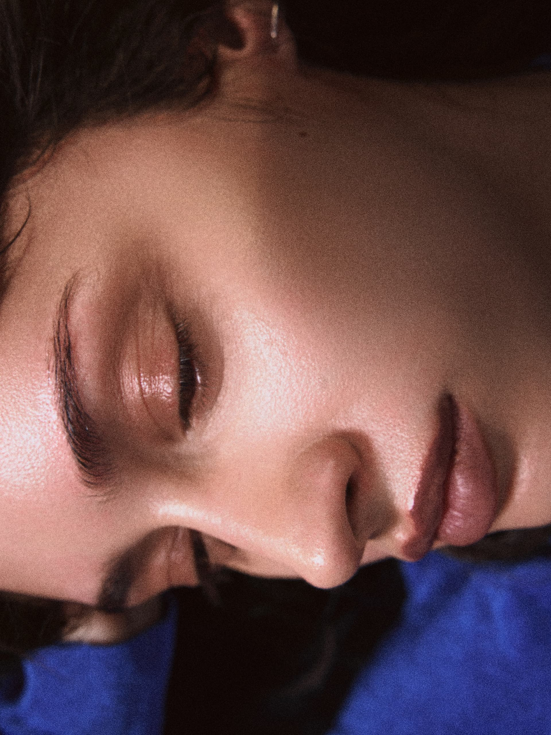 Close-up of a person with closed eyes, lying down with serene expression.