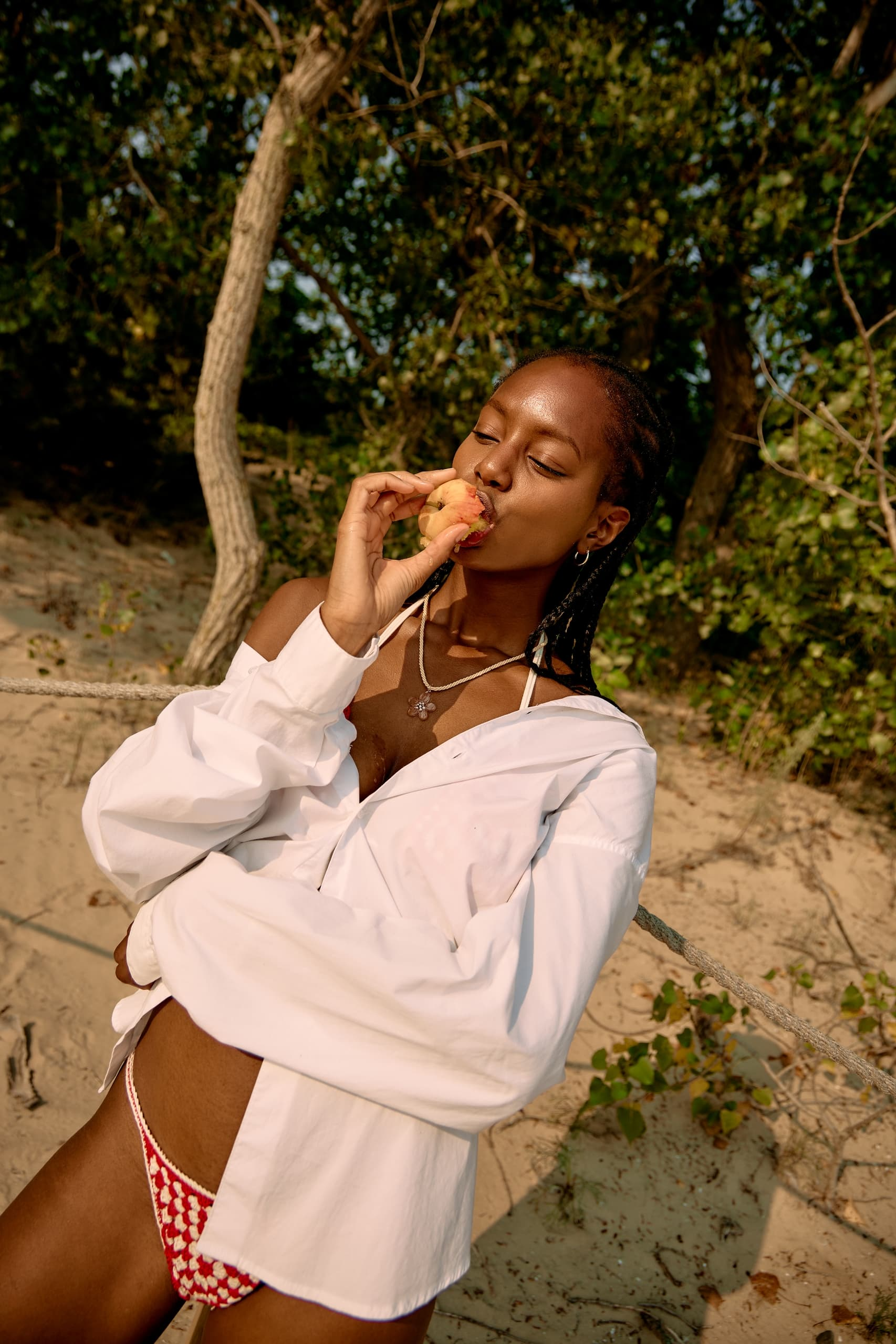 Woman enjoying a peach on a sunny beach day.