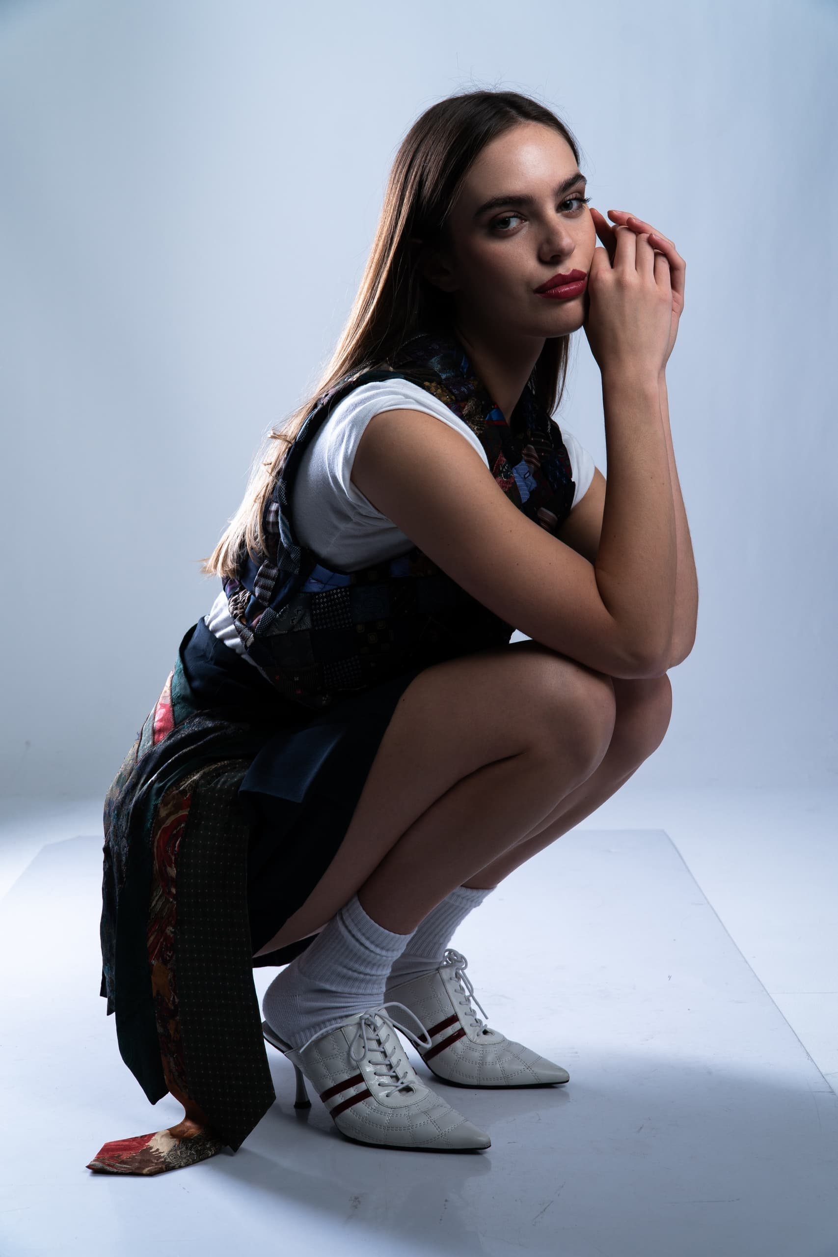 Woman in stylish outfit and heels posing on a white background.