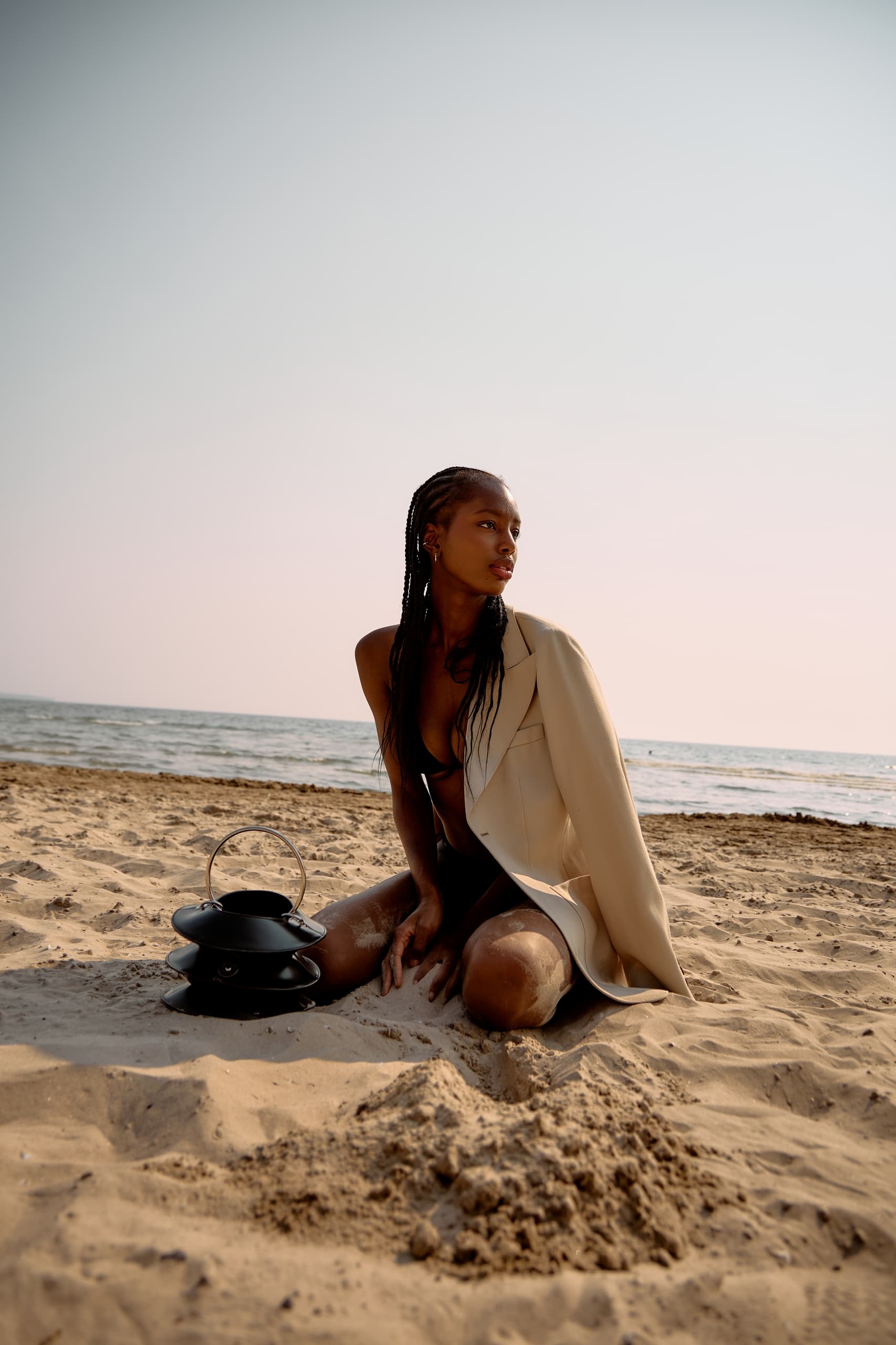 Woman on a beach in swimsuit and blazer with ocean backdrop.
