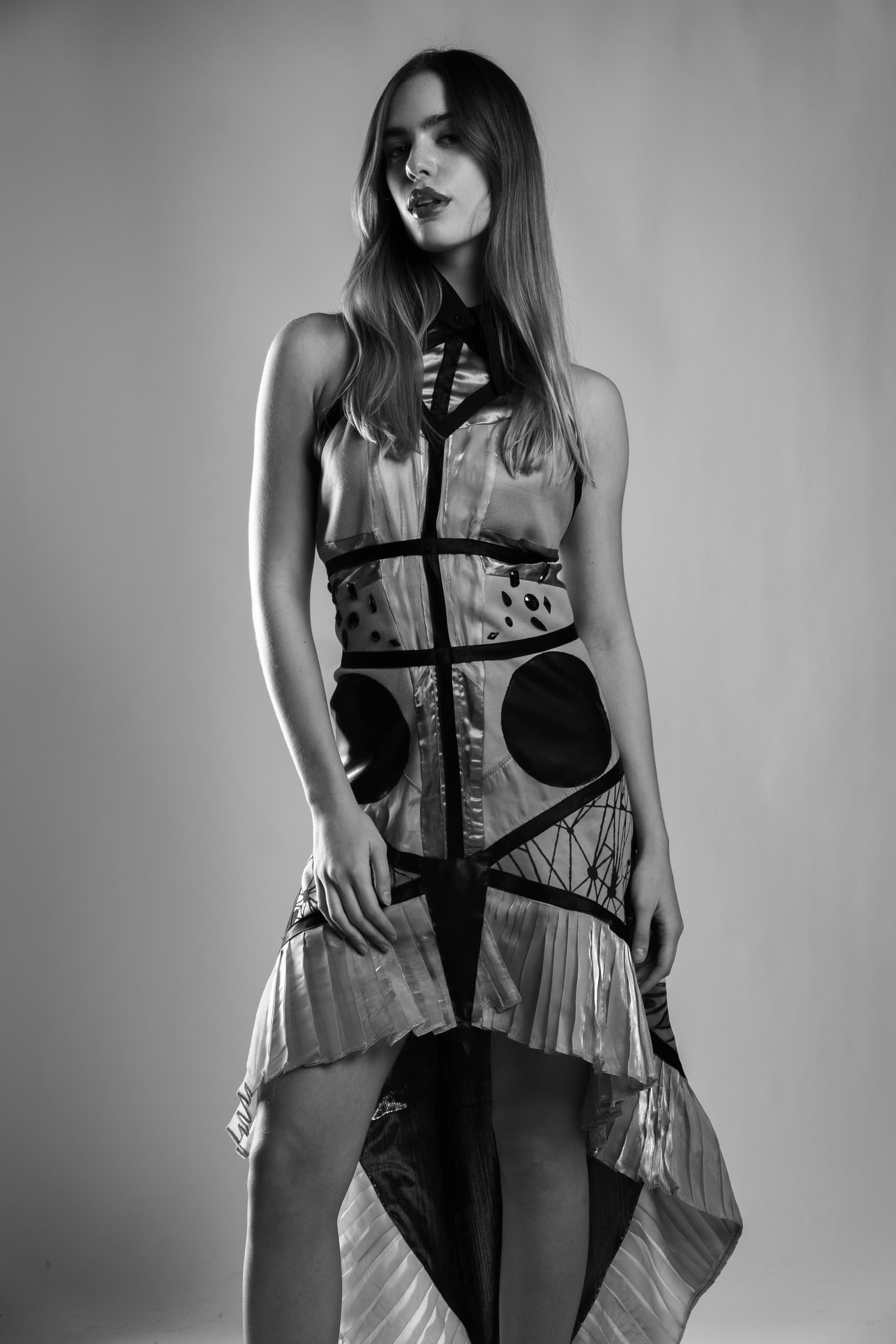 Woman in abstract patterned dress posing confidently in black and white photo.