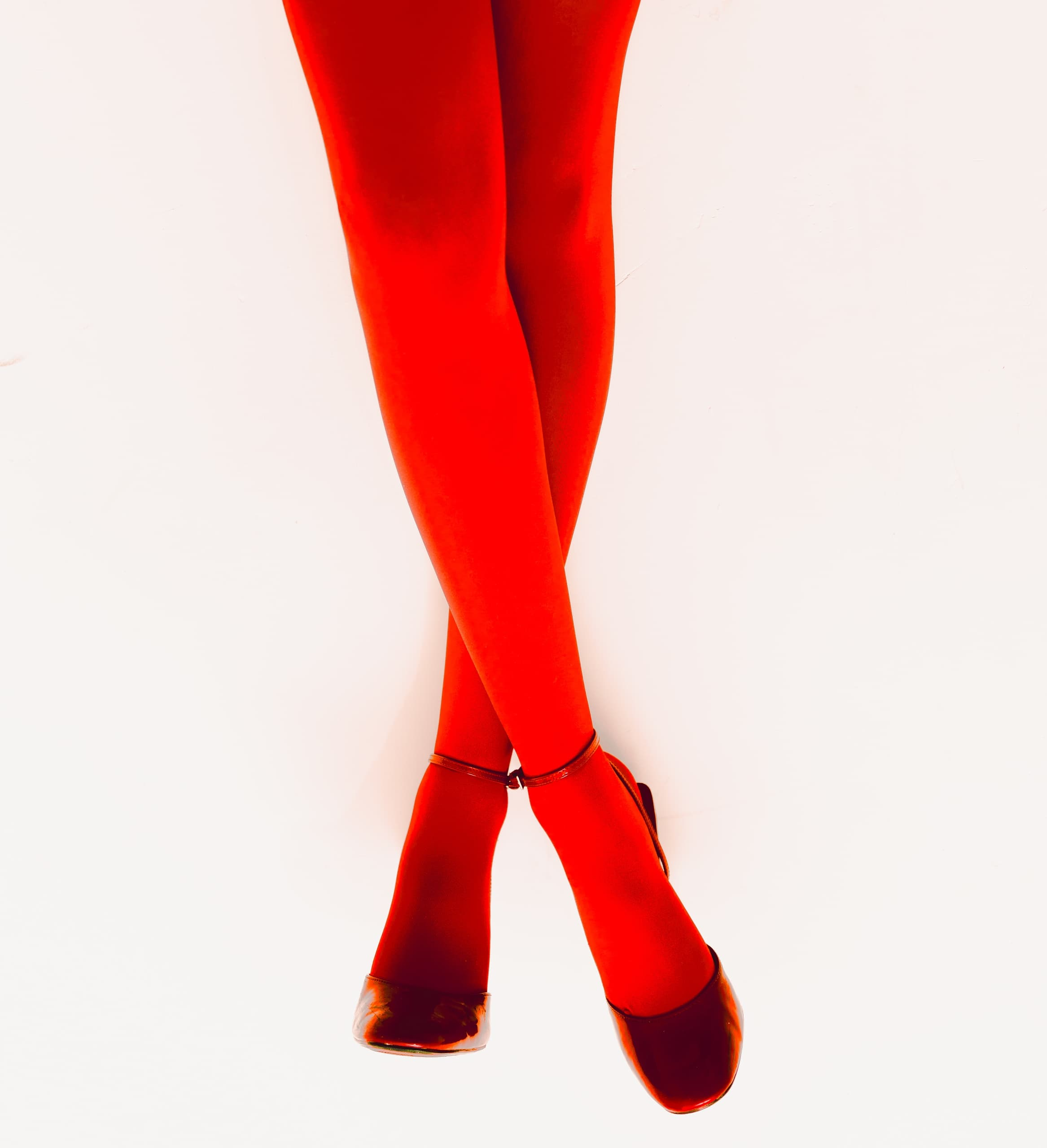 Red tights and heeled shoes against a bright background.