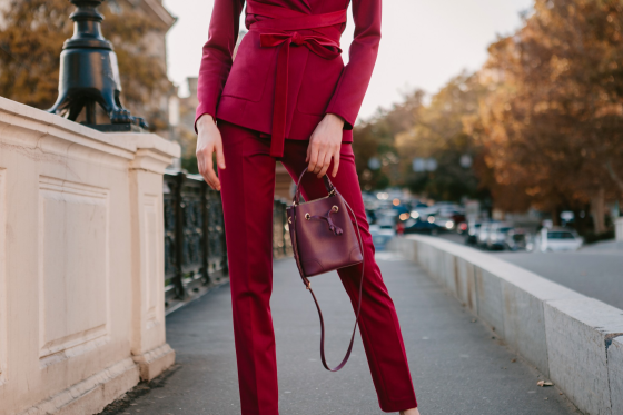 Woman in red suit with small handbag on city street.