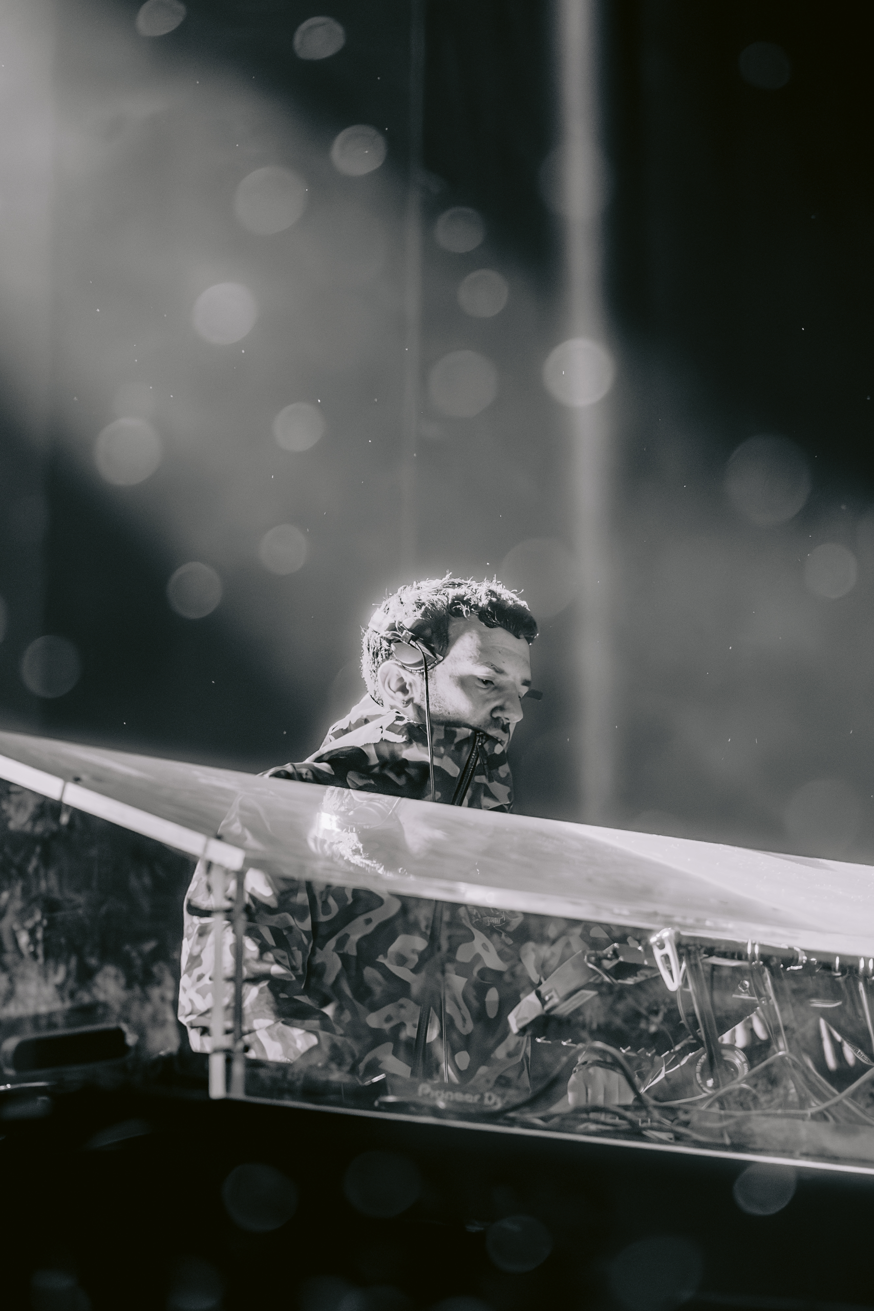 DJ performing with headphones under ambient lights.