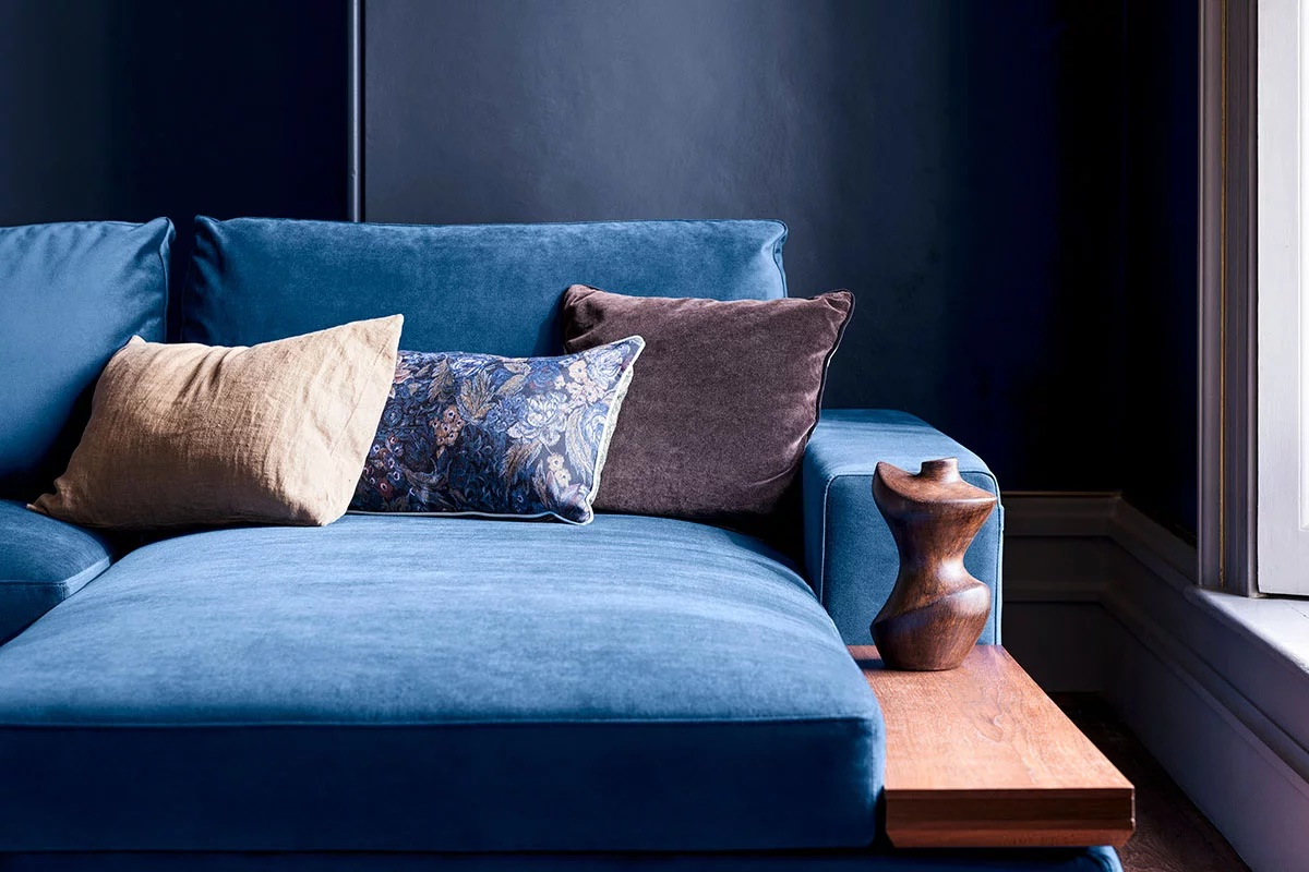 Blue velvet sofa with decorative pillows in an elegant, modern living room setting.