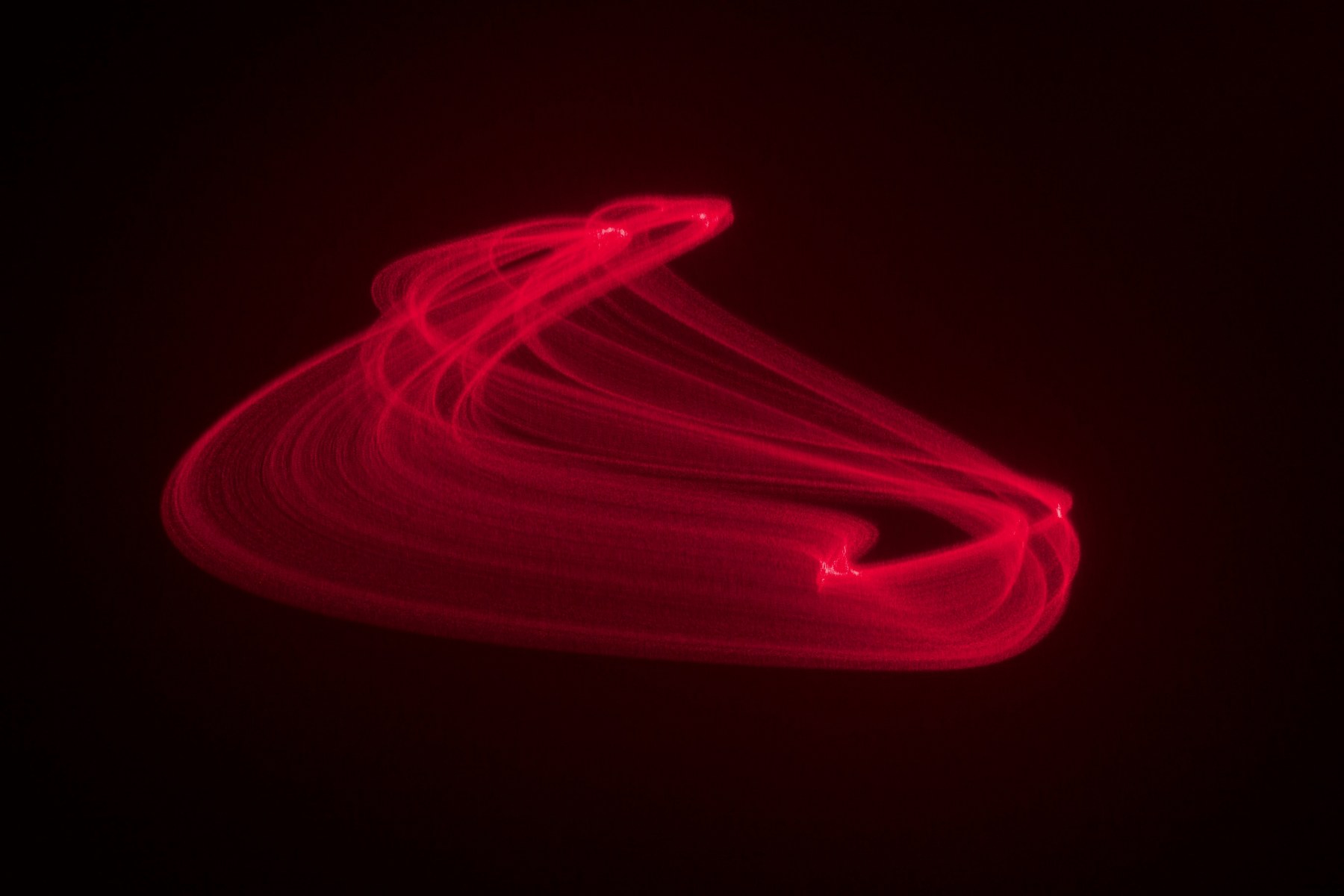 Red abstract light trails on a dark background, creating dynamic swirling patterns.
