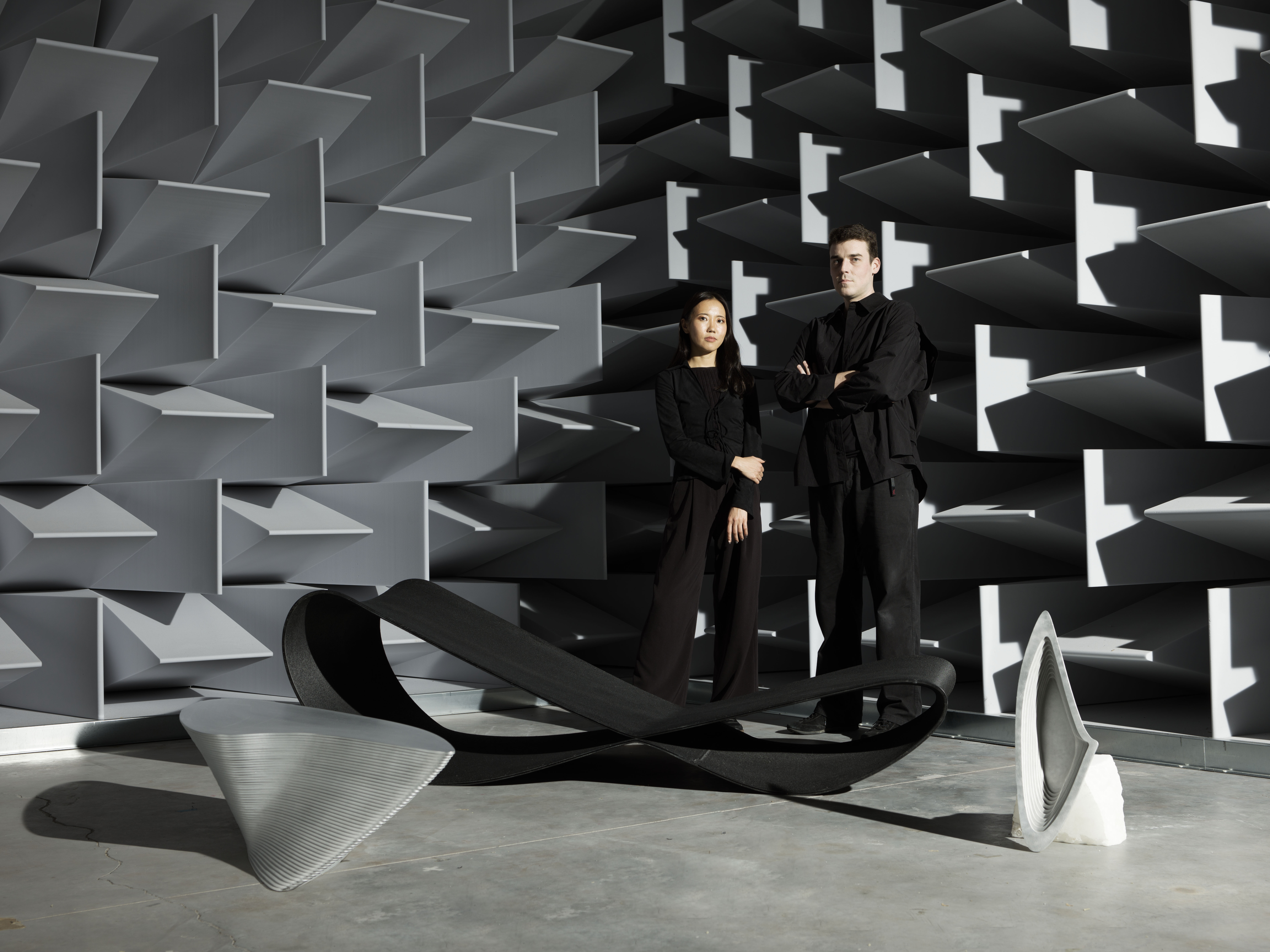 Modern art exhibit with two people, geometric designs, and anechoic chamber.