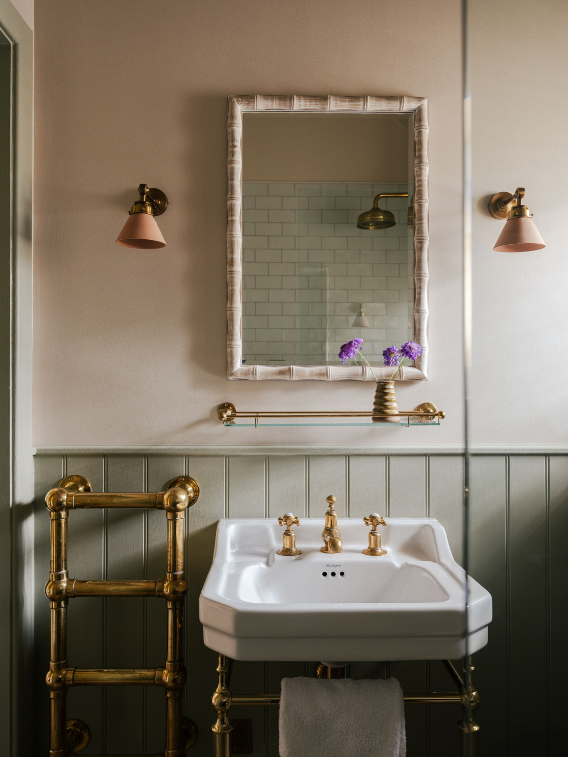 Vintage bathroom with brass fixtures, white sink, and floral accents.