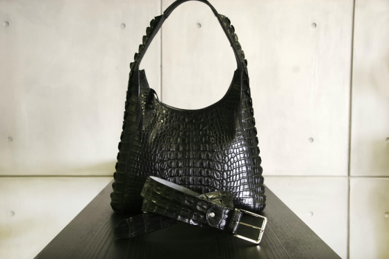 Black crocodile leather handbag and belt on display.
