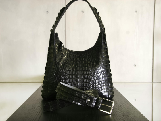 Black crocodile leather handbag and belt on display.