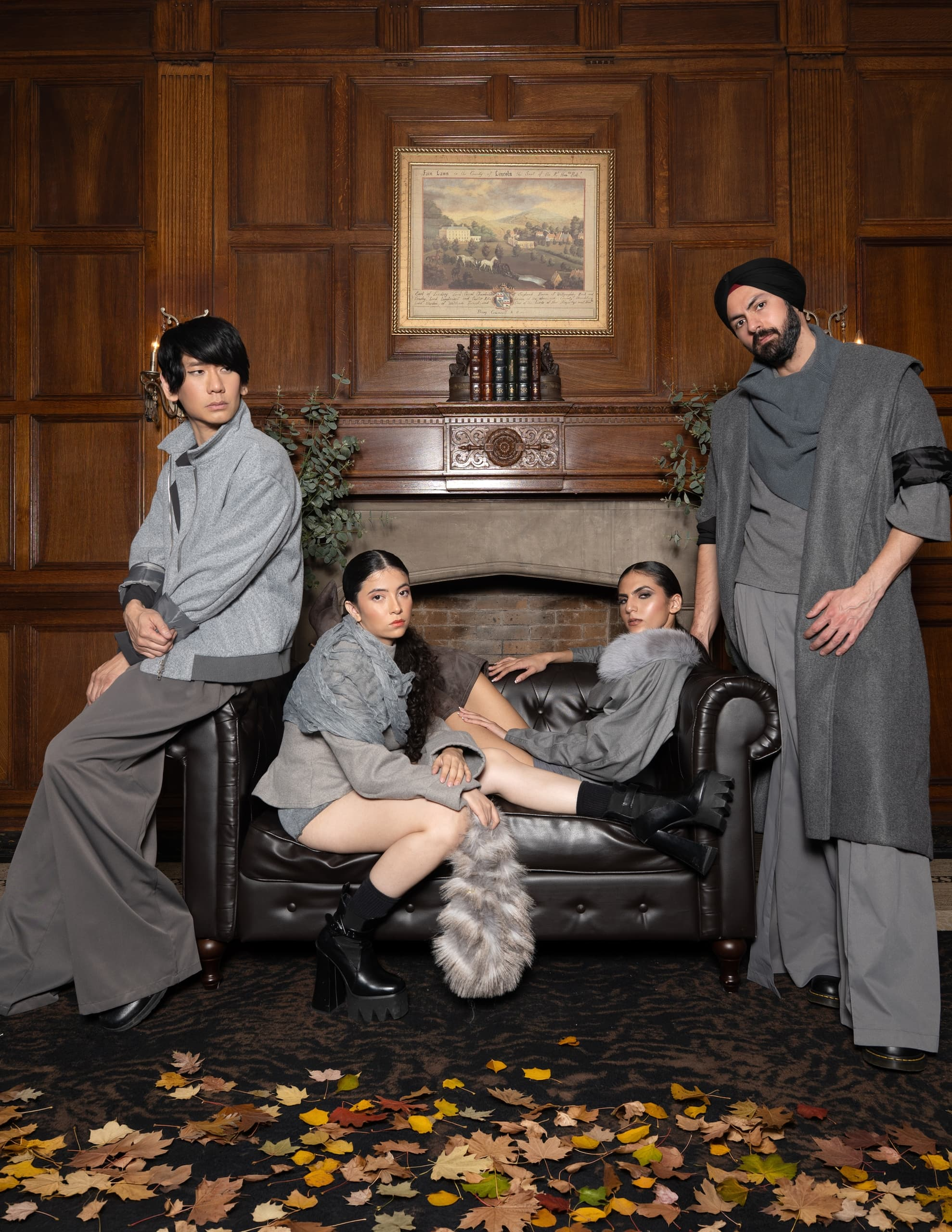 Fashion models in stylish gray outfits posing in an elegant, wood-paneled room.