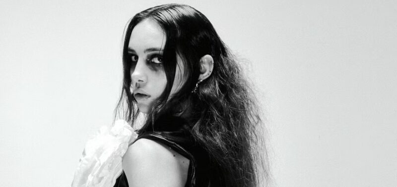 Black and white portrait of a woman with dark makeup and wavy hair.