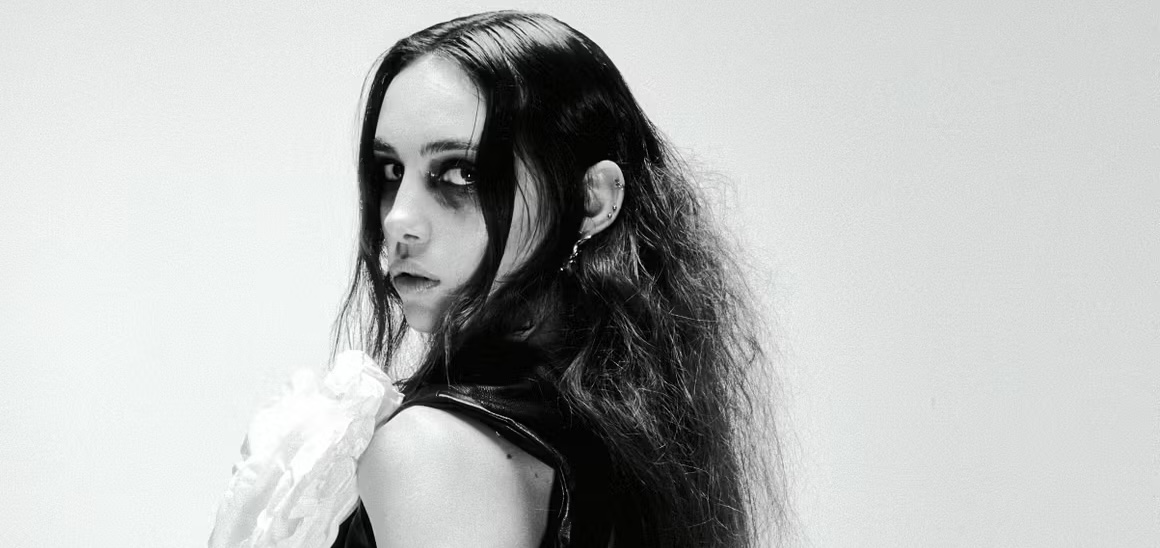 Black and white portrait of a woman with dark makeup and wavy hair.