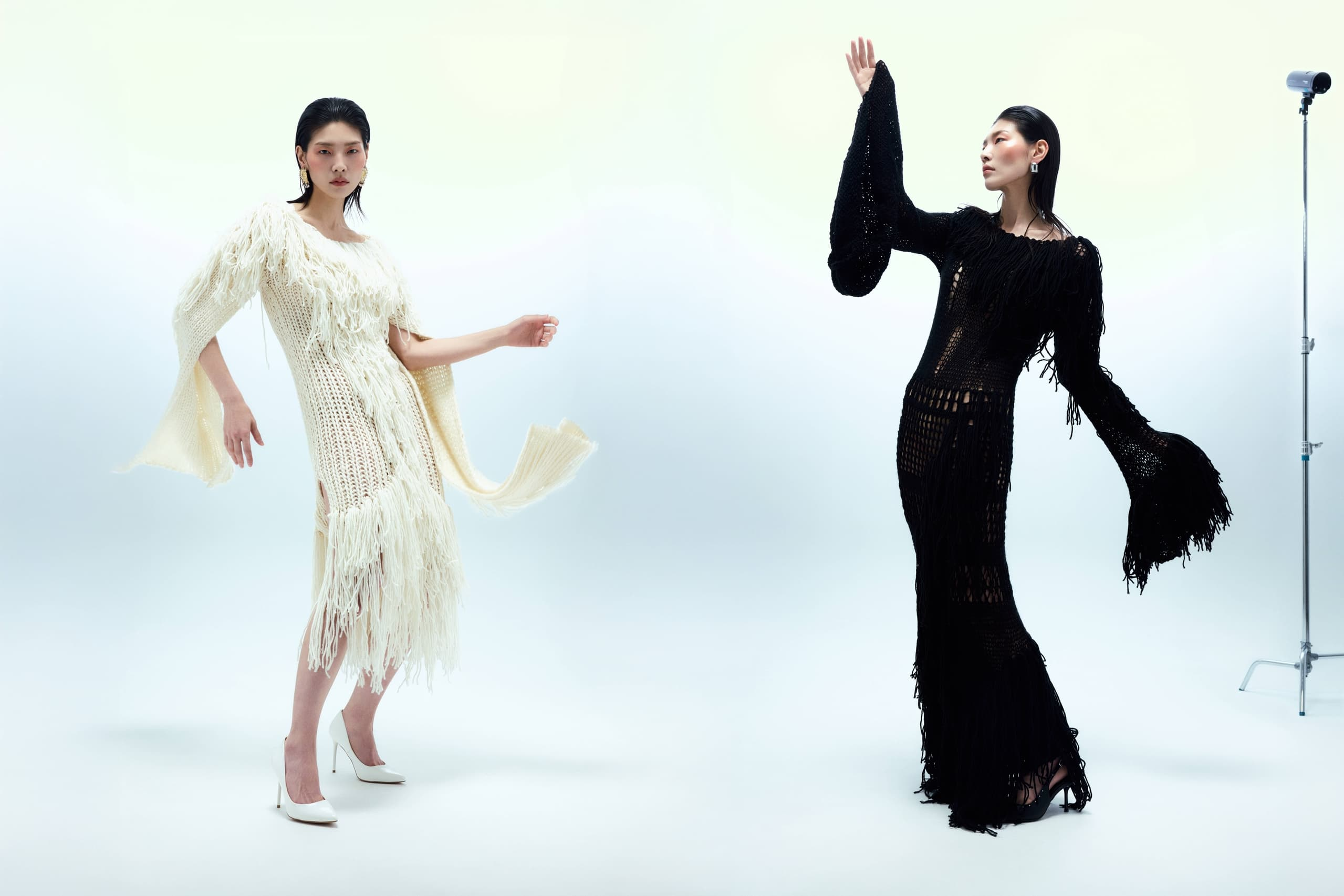 Models in stylish black and white fringe dresses striking elegant poses.