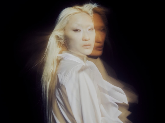 Ethereal portrait of a person in white with motion blur effect and dark background.