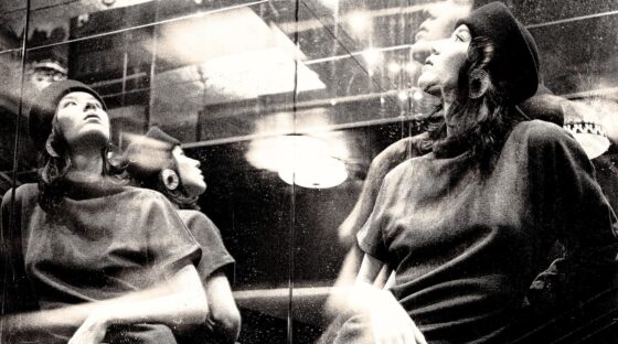 Elegant woman in beret reflected in artistic, mirrored photography.